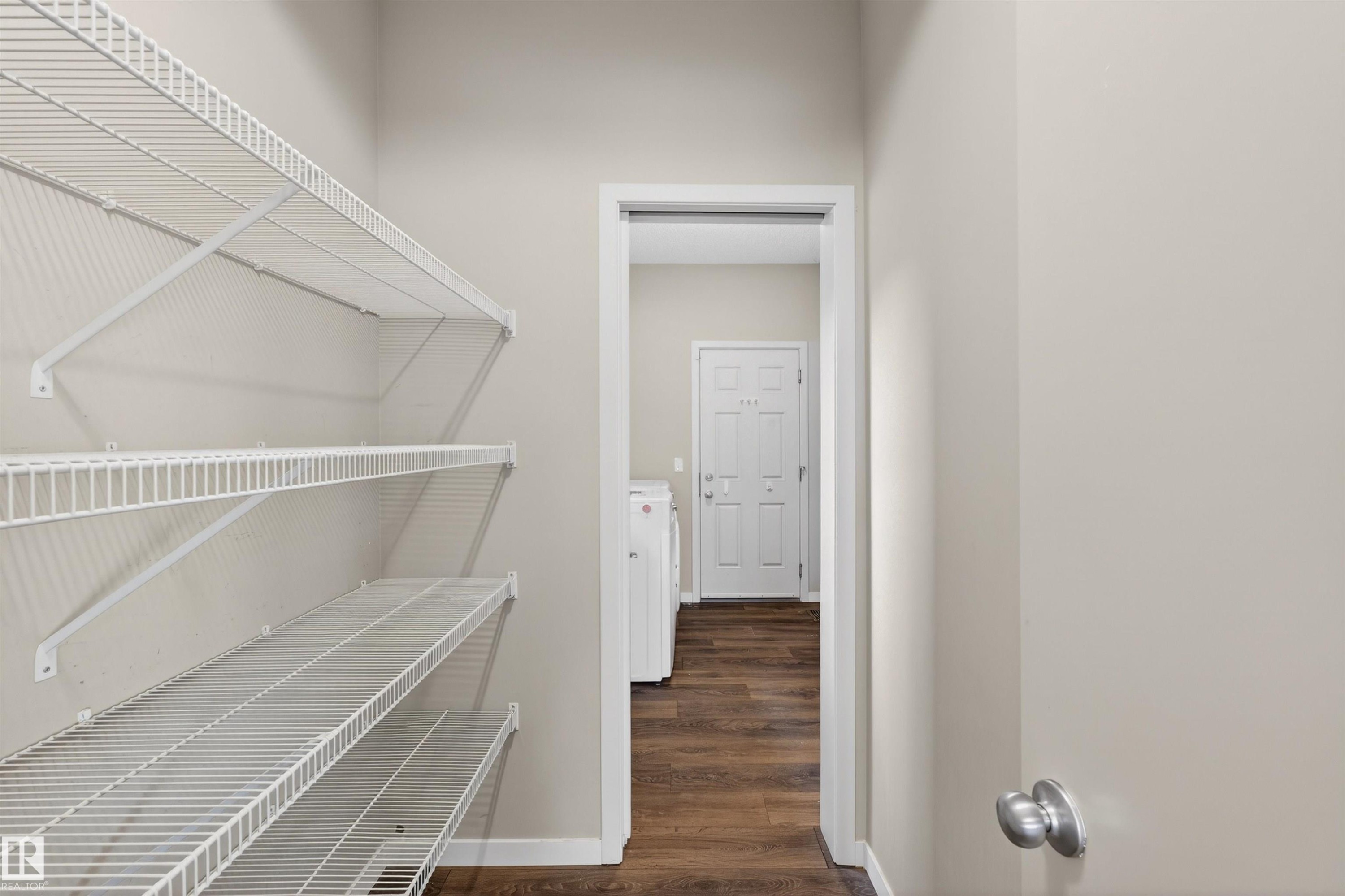 Utility area with ample wire shelving, wood-finish flooring, and neutral wall paint - 4723 Alwood Bend Sw, Edmonton, AB - Indoor With Storage