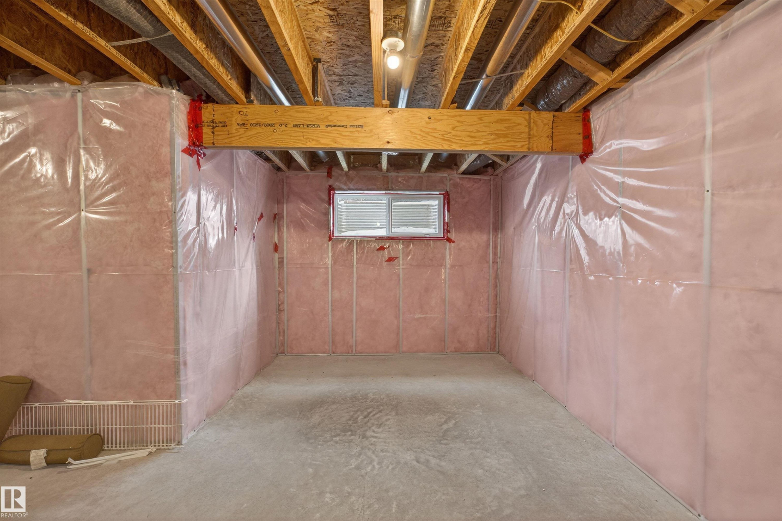 Unfinished basement space featuring exposed wood joists, structural beam, concrete flooring, and insulated walls with vapor barrier - 4723 Alwood Bend Sw, Edmonton, AB - Indoor Photo Showing Basement