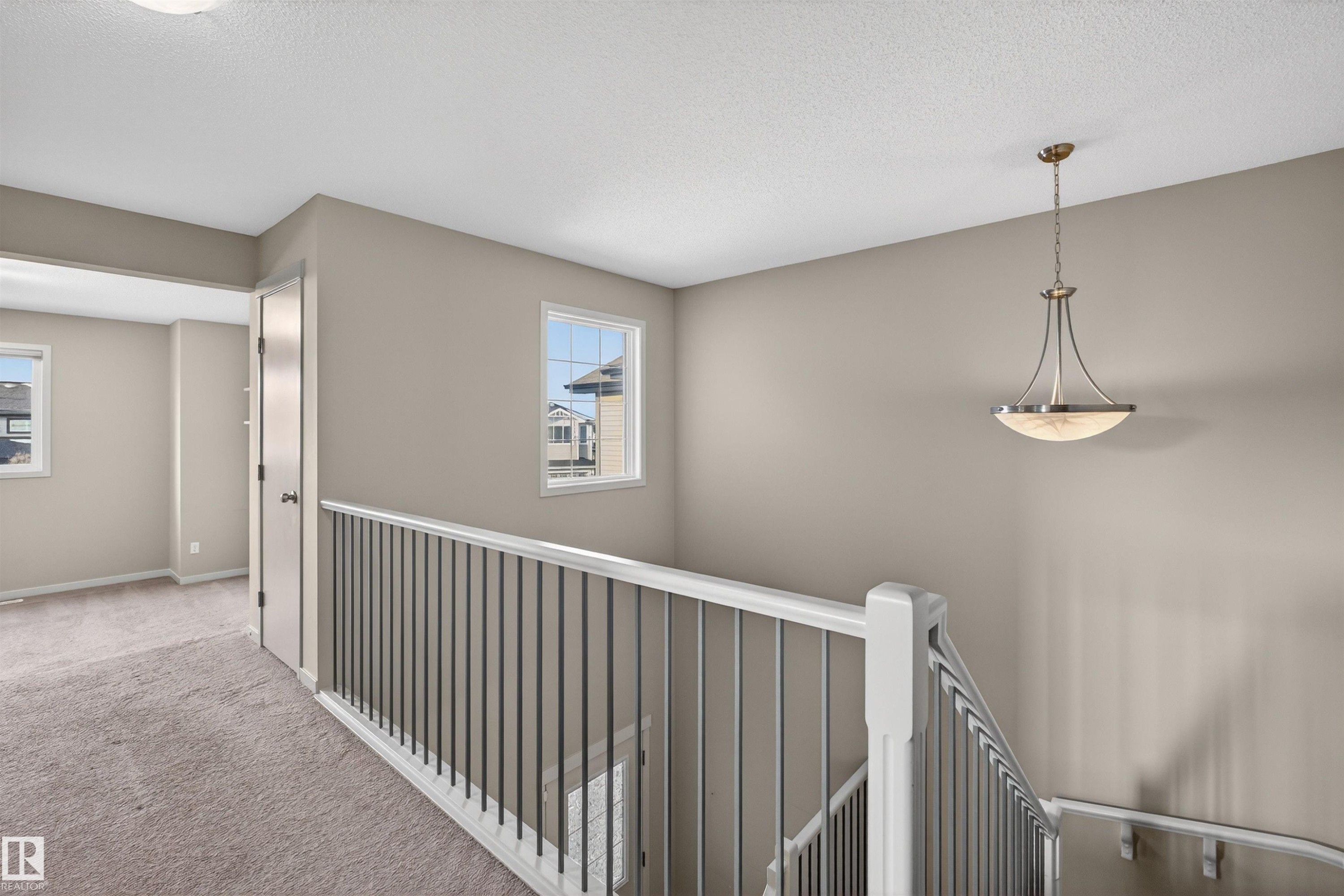 Upper-level landing featuring a staircase with a white railing and dark balusters, neutral wall paint, and recessed lighting - 4723 Alwood Bend Sw, Edmonton, AB - Indoor Photo Showing Other Room