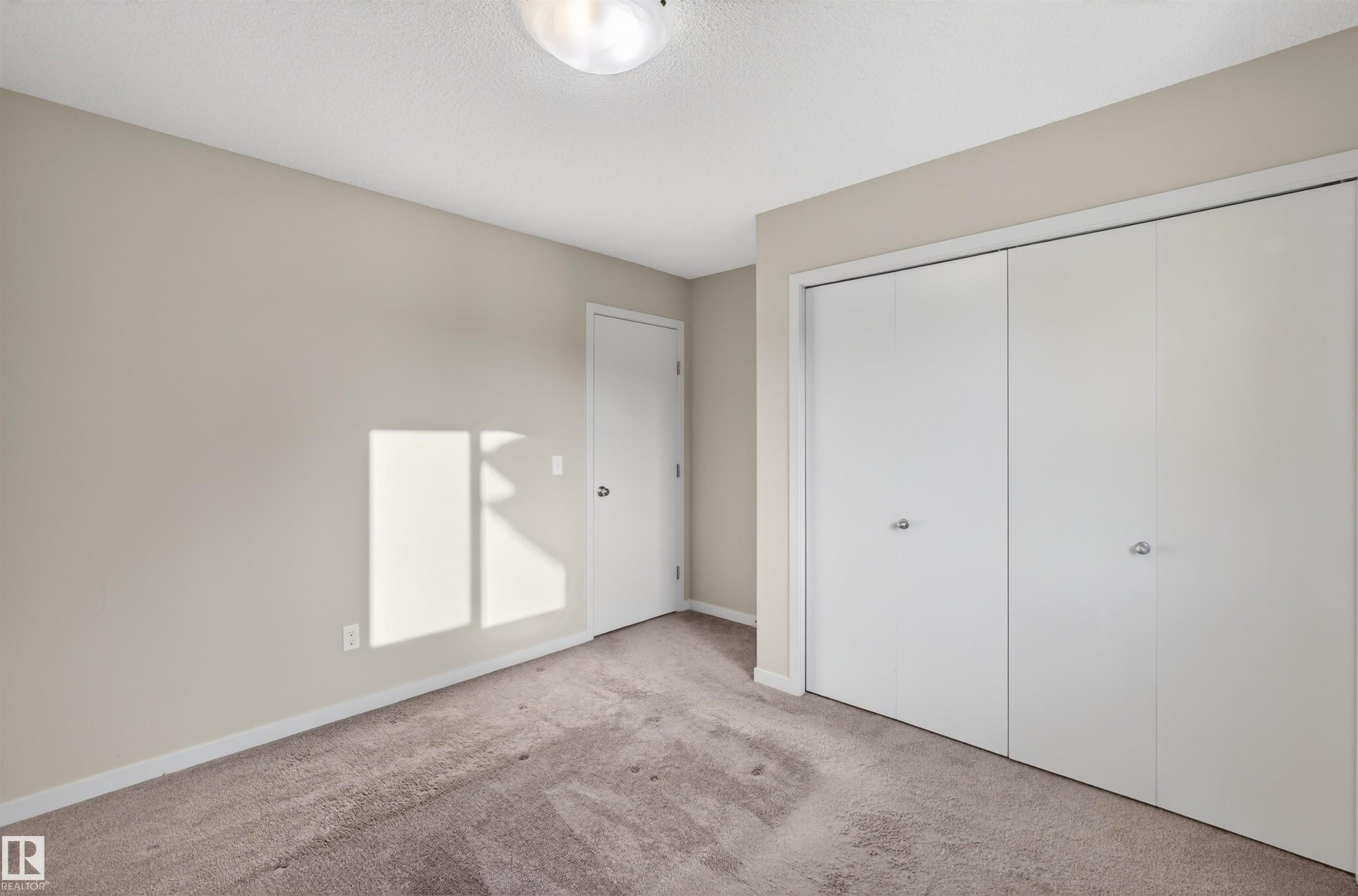 Neutral-toned interior with light tan walls, a textured ceiling, and a flush mount ceiling light fixture - 4723 Alwood Bend Sw, Edmonton, AB - Indoor Photo Showing Other Room