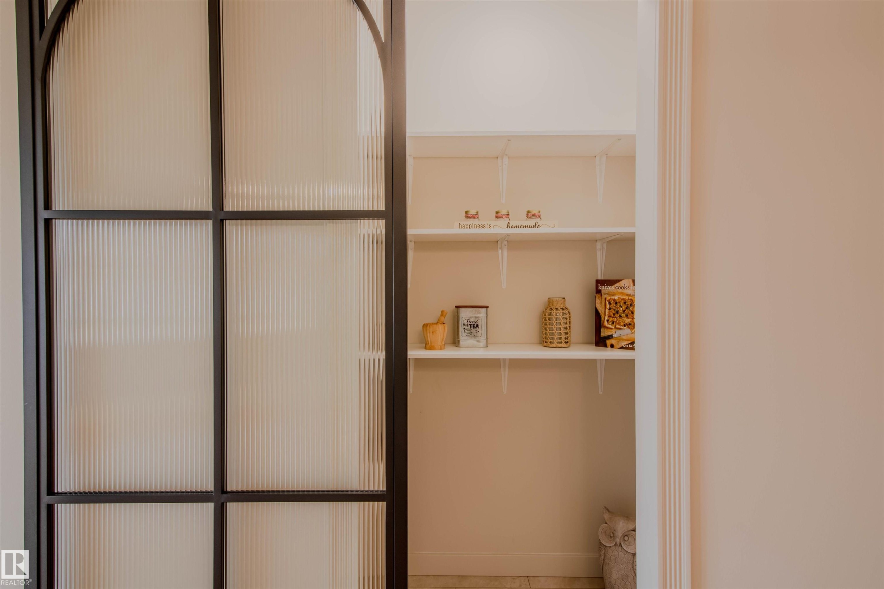 Black-framed sliding door with reeded glass panels, revealing interior shelving - 5935 189 Street, Edmonton, AB - Indoor