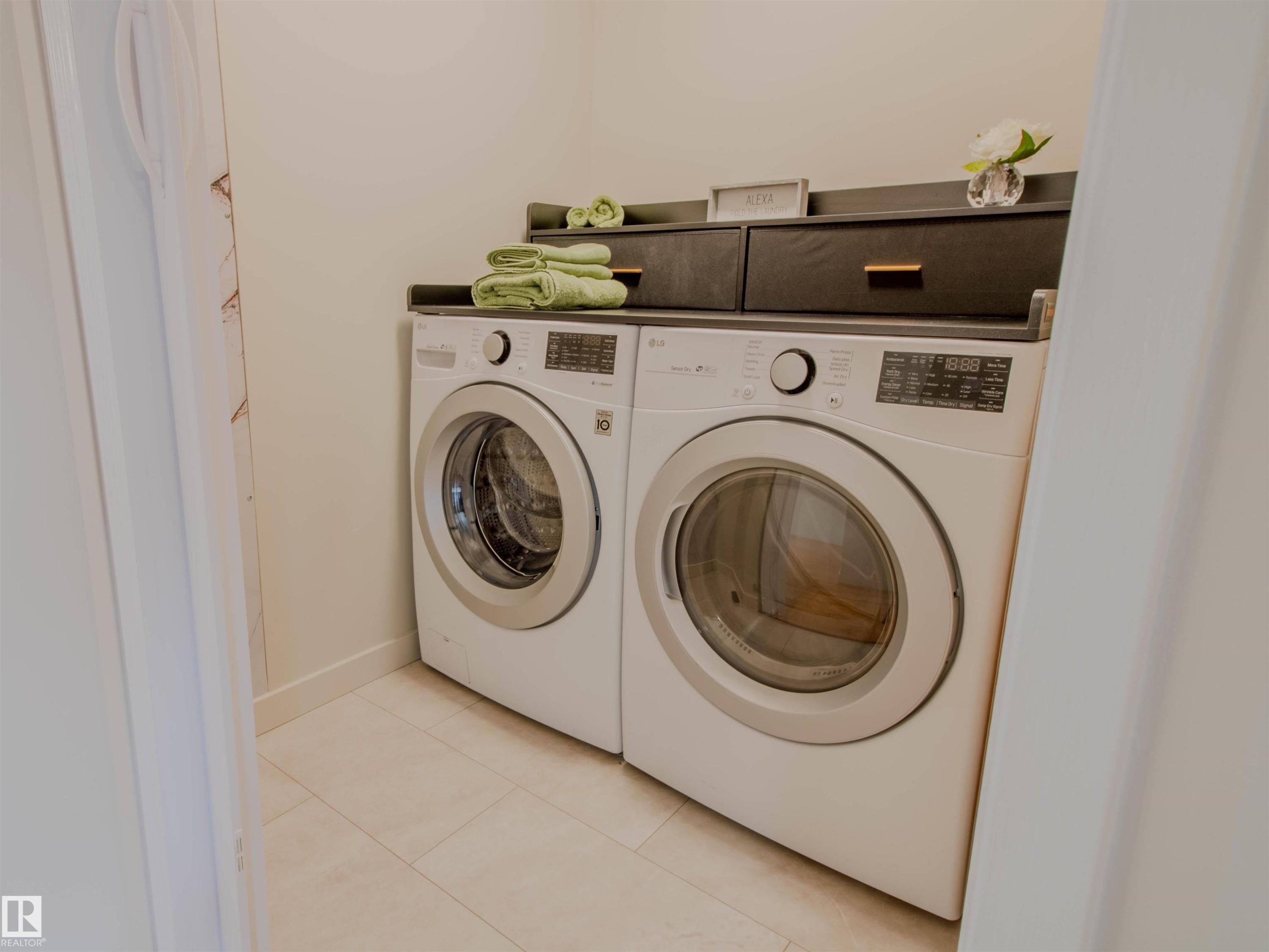 Laundry area featuring a side-by-side washer and dryer, light-toned tile flooring, and a built-in dark shelving unit with integrated storage - 5935 189 Street, Edmonton, AB - Indoor Photo Showing Laundry Room