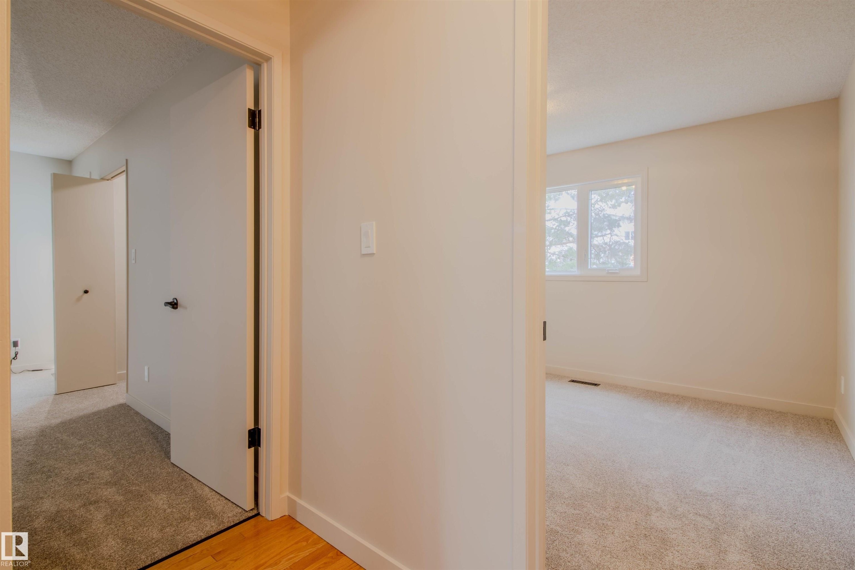 Carpeted hallway with wood-finish flooring transition - 5935 189 Street, Edmonton, AB - Indoor Photo Showing Other Room