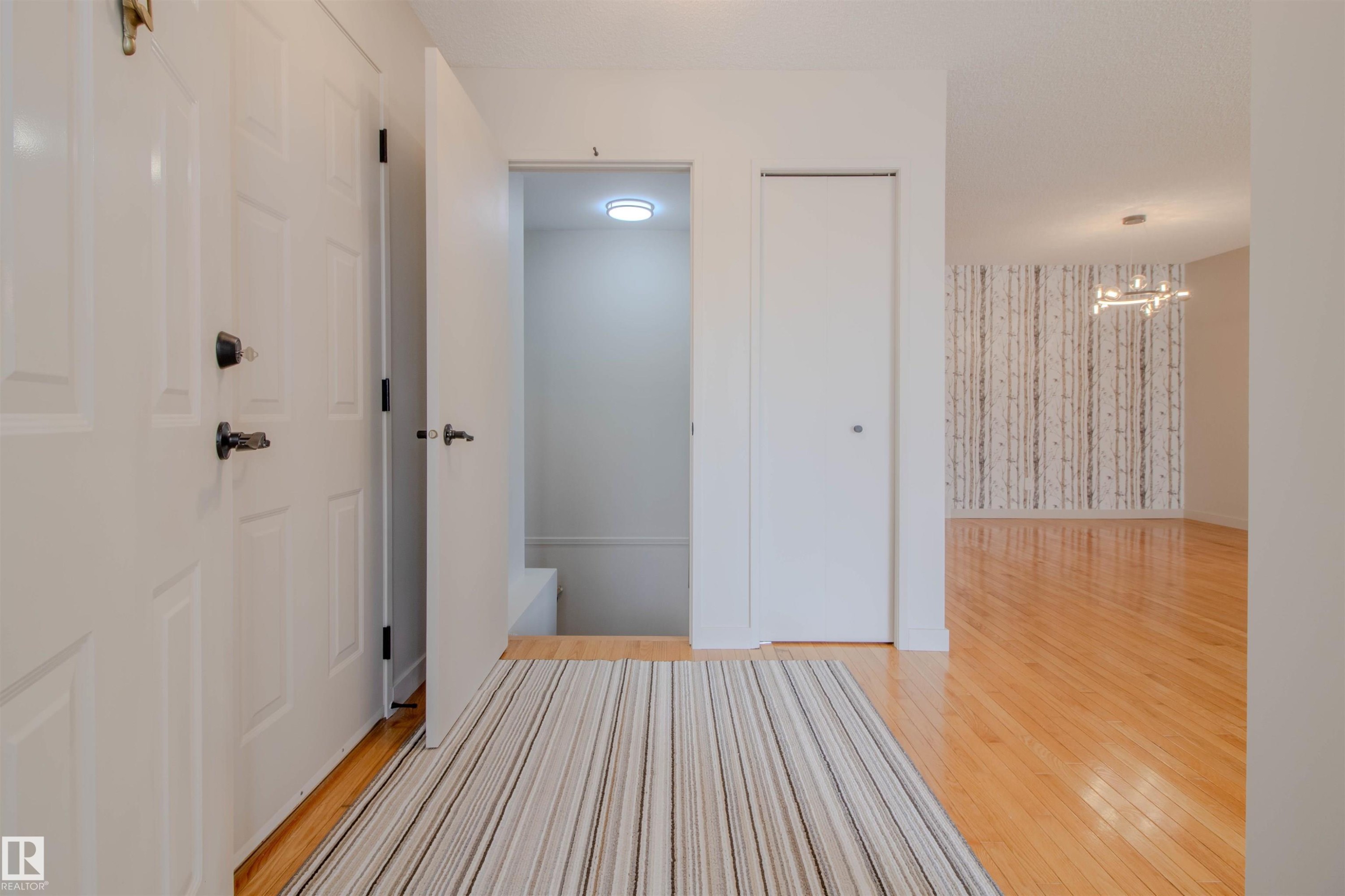 Welcoming entryway featuring hardwood flooring, a white paneled entrance door, and a discrete closet - 5935 189 Street, Edmonton, AB - Indoor Photo Showing Other Room