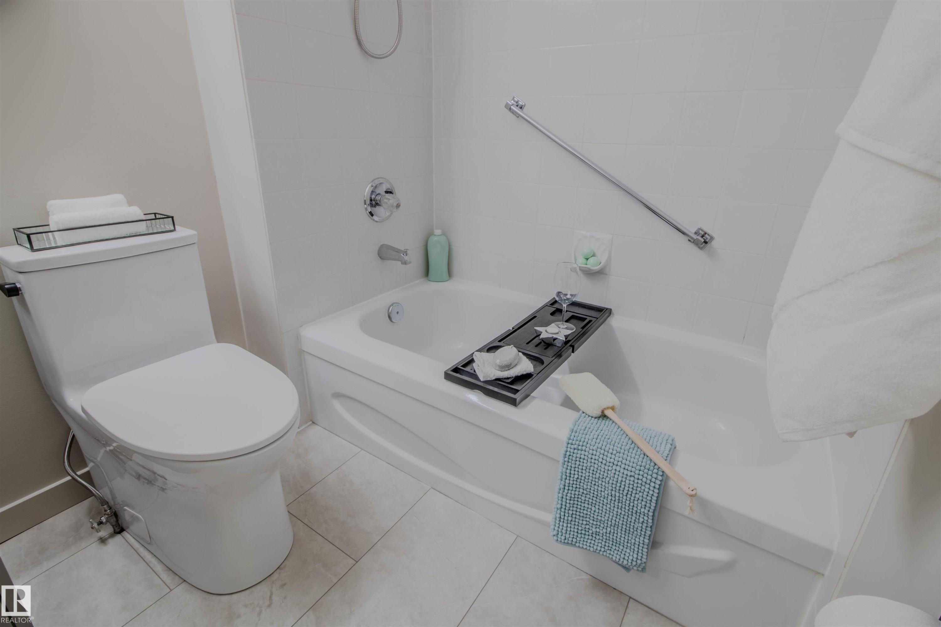 Bathroom featuring a deep soaking tub with chrome fixtures, a wall-mounted grab bar, and a two-piece toilet - 5935 189 Street, Edmonton, AB - Indoor Photo Showing Bathroom