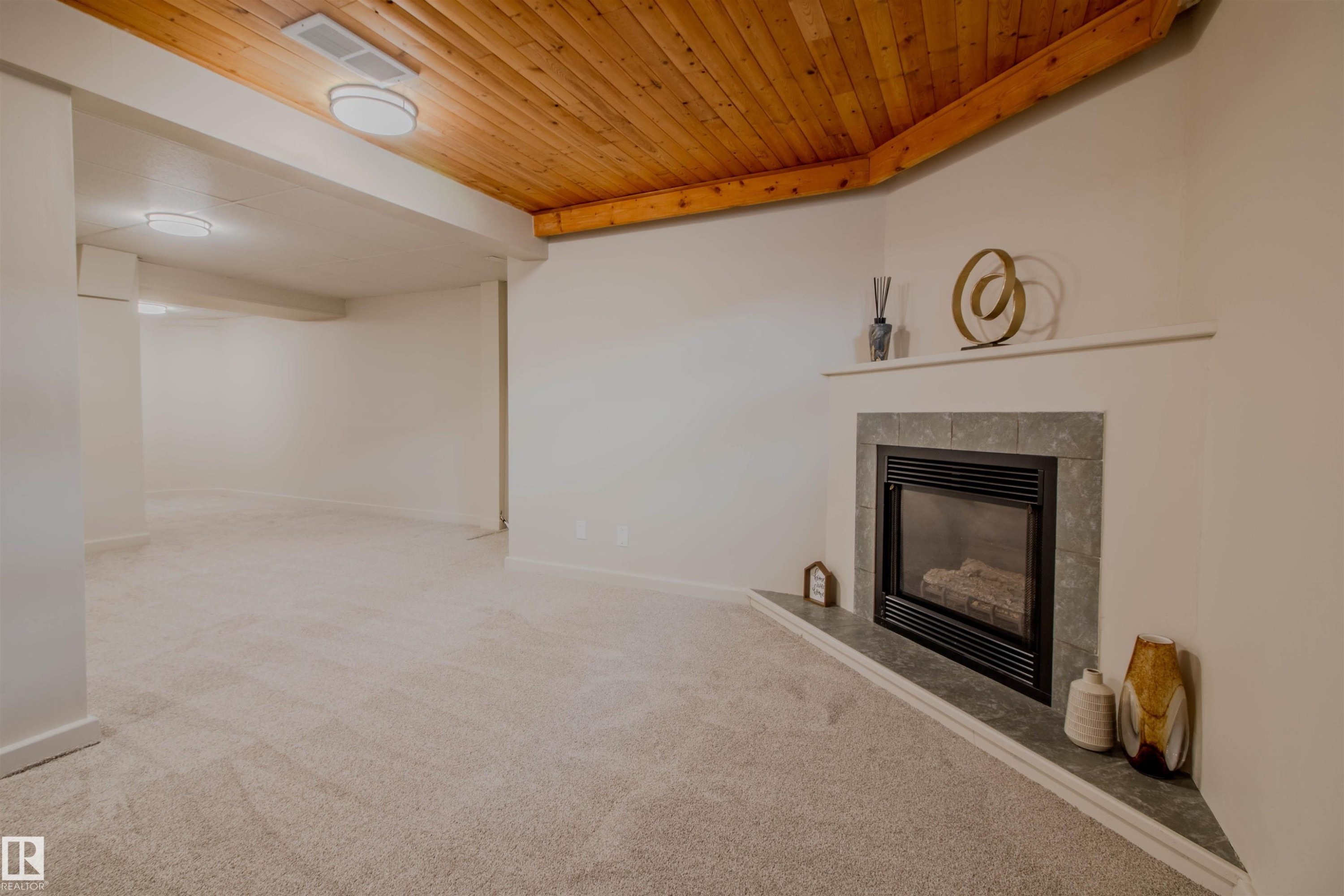 Corner fireplace with a tiled surround and hearth, set against light-toned walls and new carpet flooring - 5935 189 Street, Edmonton, AB - Indoor With Fireplace