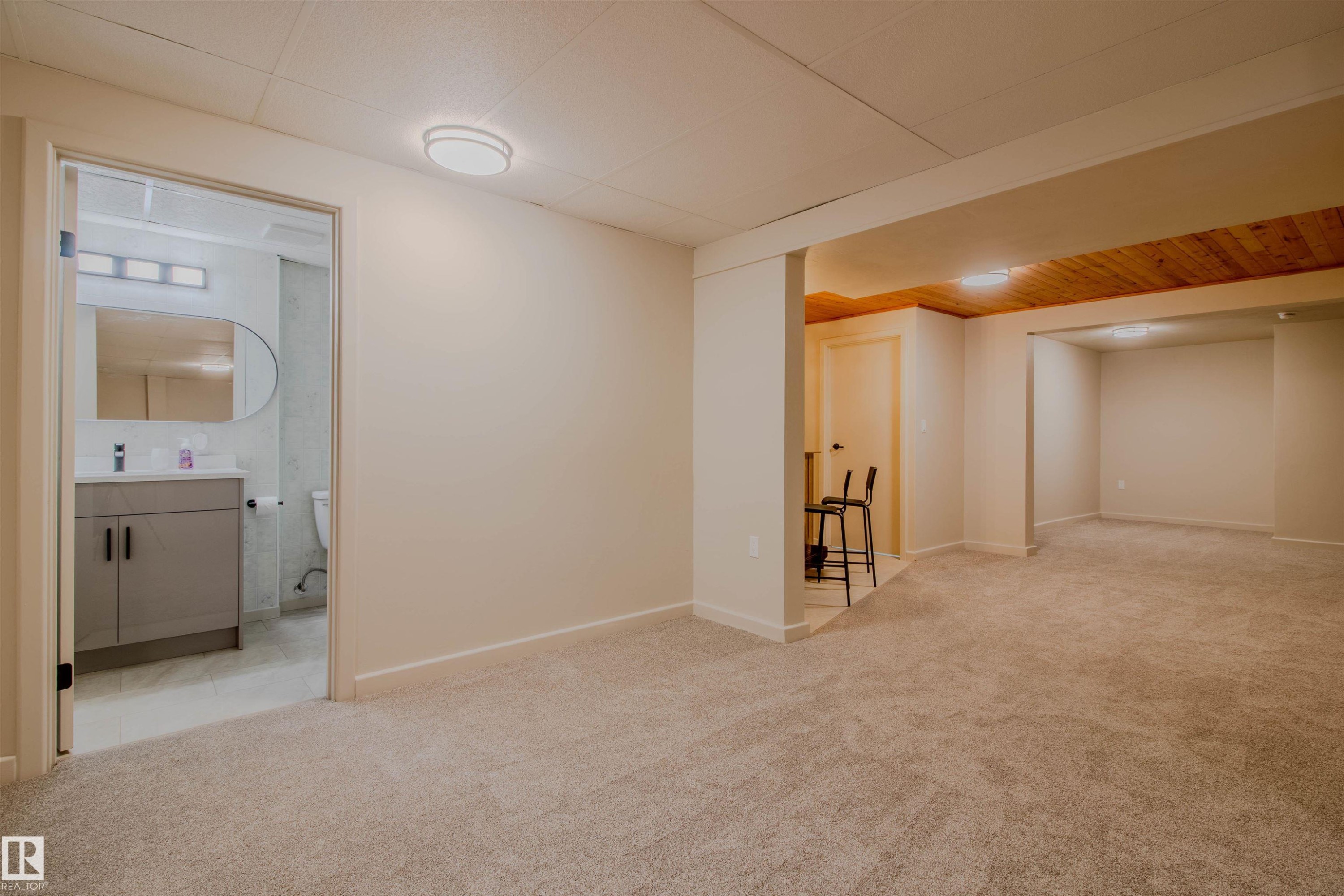 Expansive carpeted area with recessed lighting and a wood-panel accent ceiling - 5935 189 Street, Edmonton, AB - Indoor