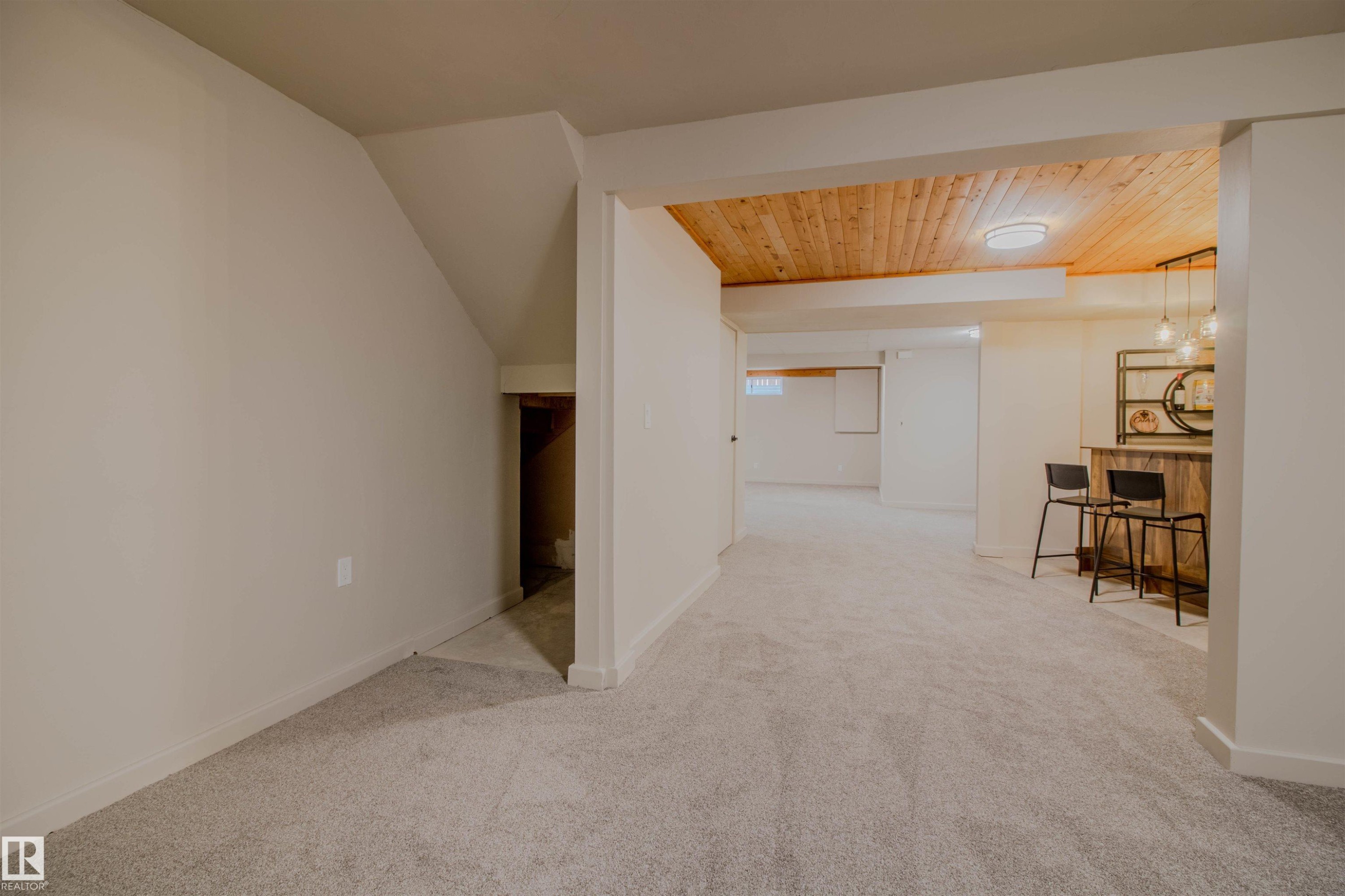 Finished lower level featuring a built-in bar with wood-look counter, wood-paneled ceiling with recessed lighting, and soft grey carpeting - 5935 189 Street, Edmonton, AB - Indoor Photo Showing Other Room