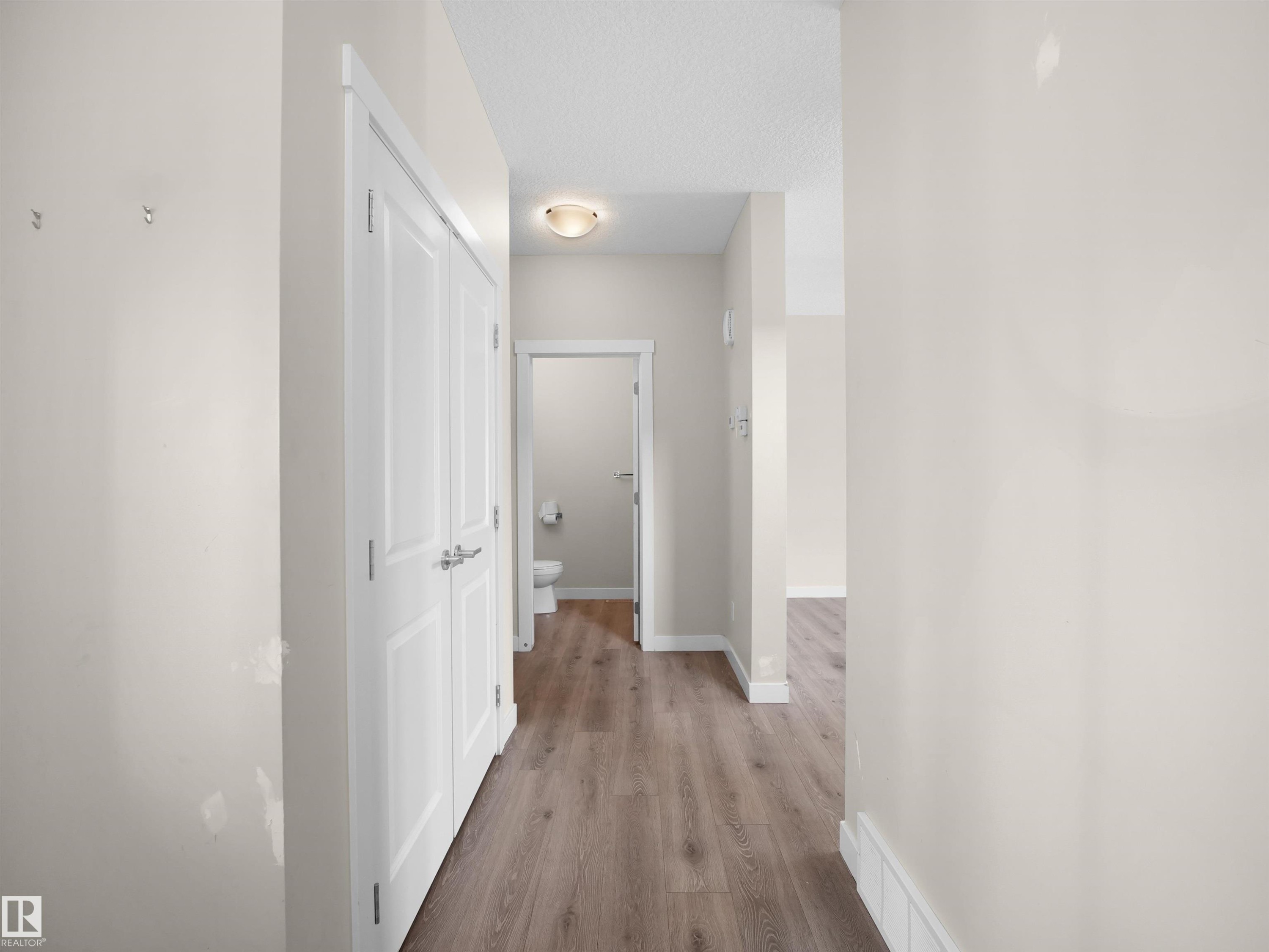 Hallway featuring wood-finish flooring, white baseboards, and a flush-mount ceiling light fixture - 8921 217 Street Nw, Edmonton, AB - Indoor Photo Showing Other Room