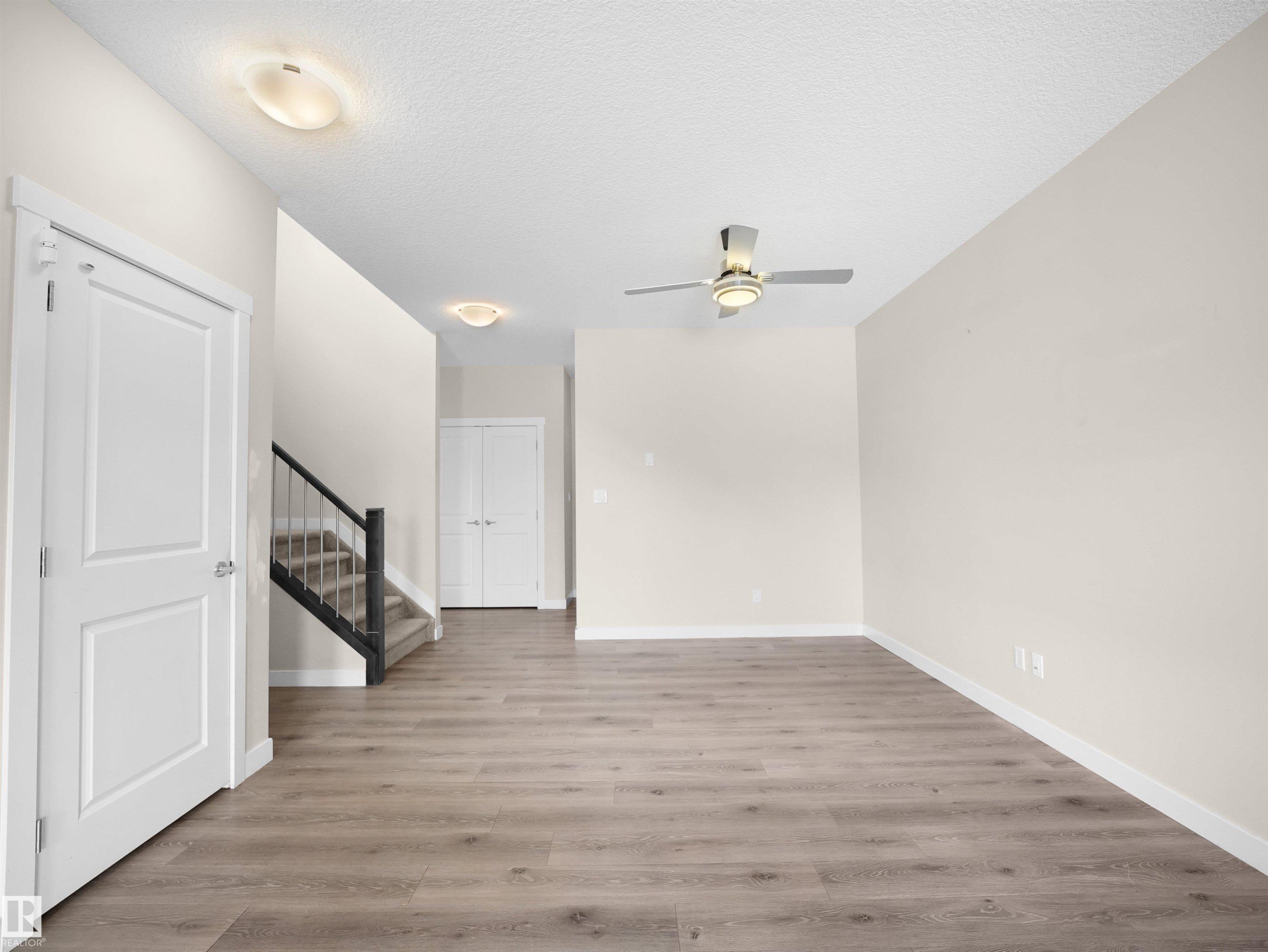 Open-concept interior featuring wood-finish flooring, light neutral wall tones, and white trim - 8921 217 Street Nw, Edmonton, AB - Indoor Photo Showing Other Room