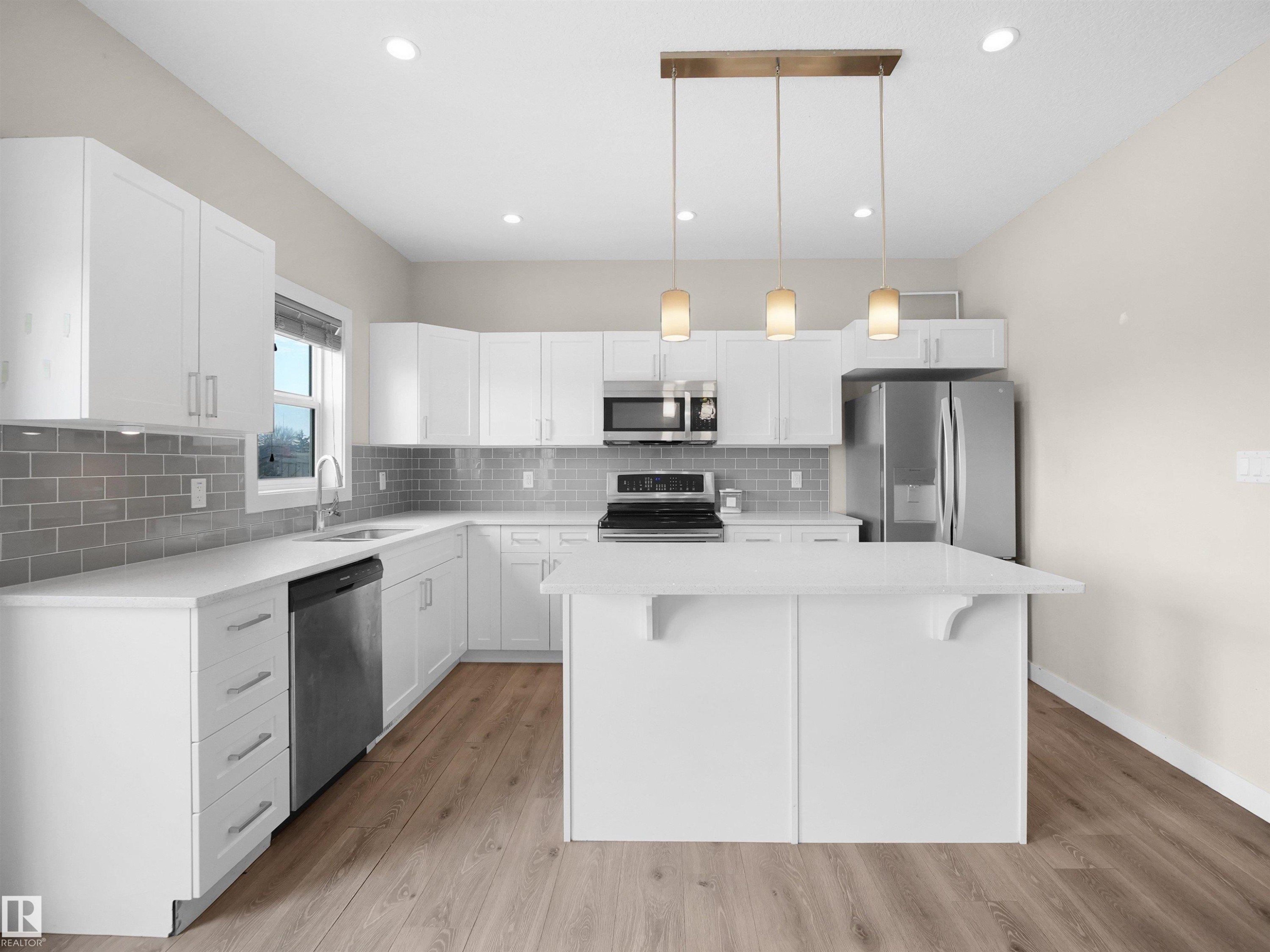 Kitchen featuring white shaker cabinetry, stainless steel appliances, a subway tile backsplash, and an island with pendant lighting - 8921 217 Street Nw, Edmonton, AB - Indoor Photo Showing Kitchen With Upgraded Kitchen