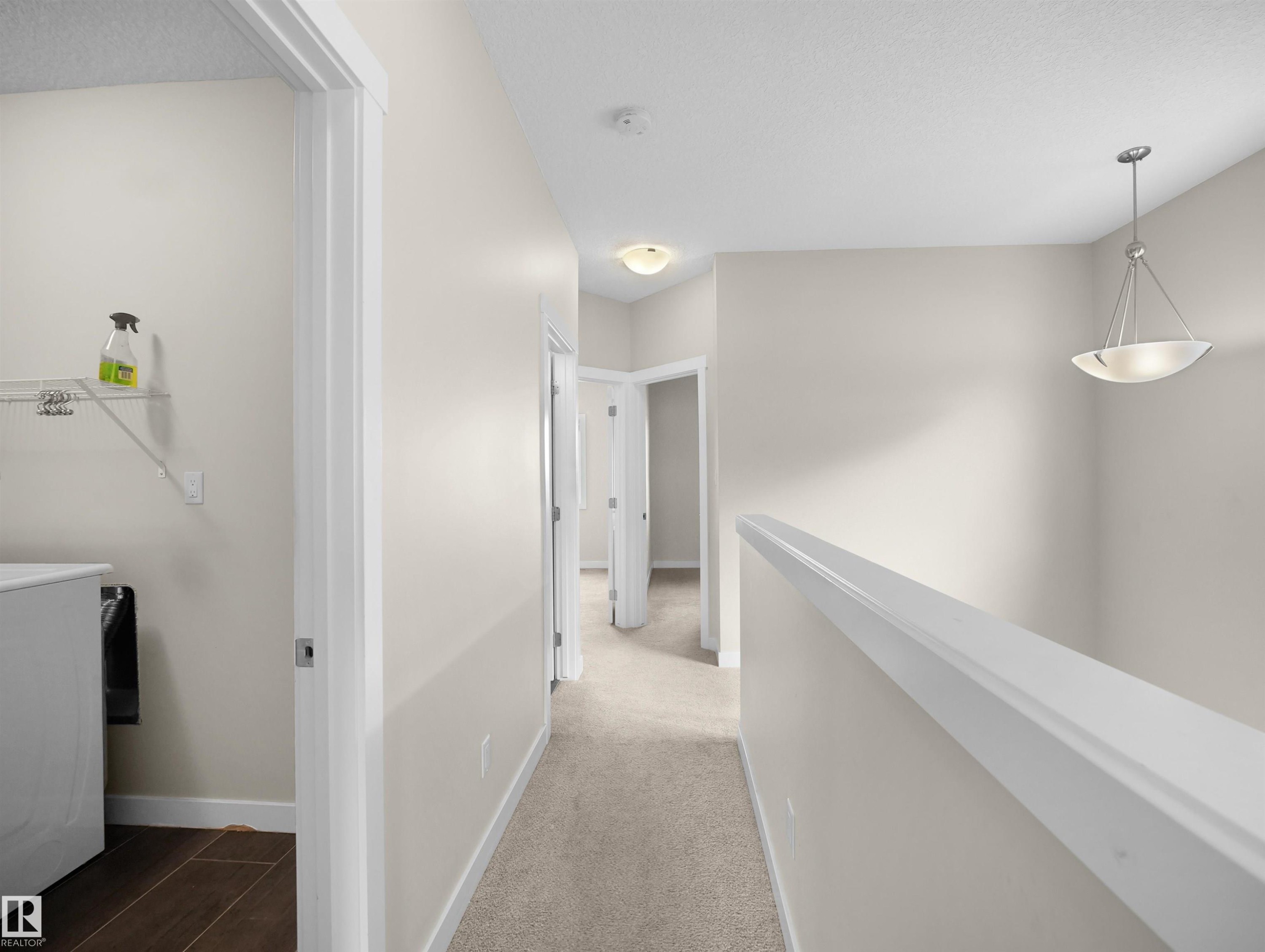 Upper-level hallway featuring neutral wall paint, carpet flooring, and a contemporary chandelier - 8921 217 Street Nw, Edmonton, AB - Indoor Photo Showing Other Room
