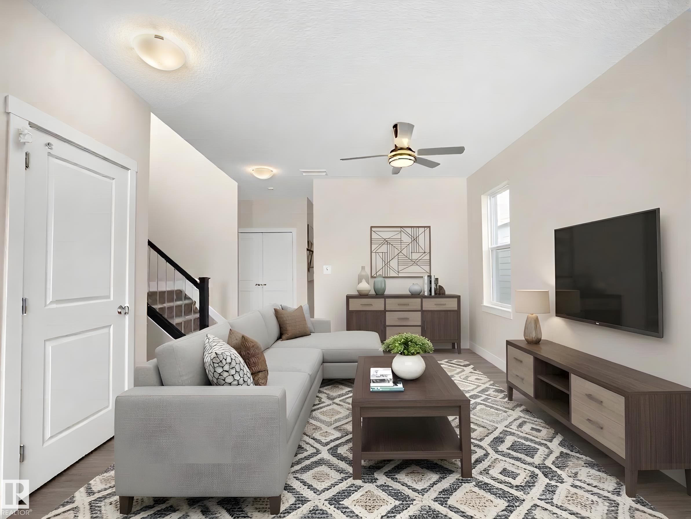 Living area featuring wood-finish flooring, a ceiling fan with integrated lighting, and multiple windows - 8921 217 Street Nw, Edmonton, AB - Indoor Photo Showing Living Room