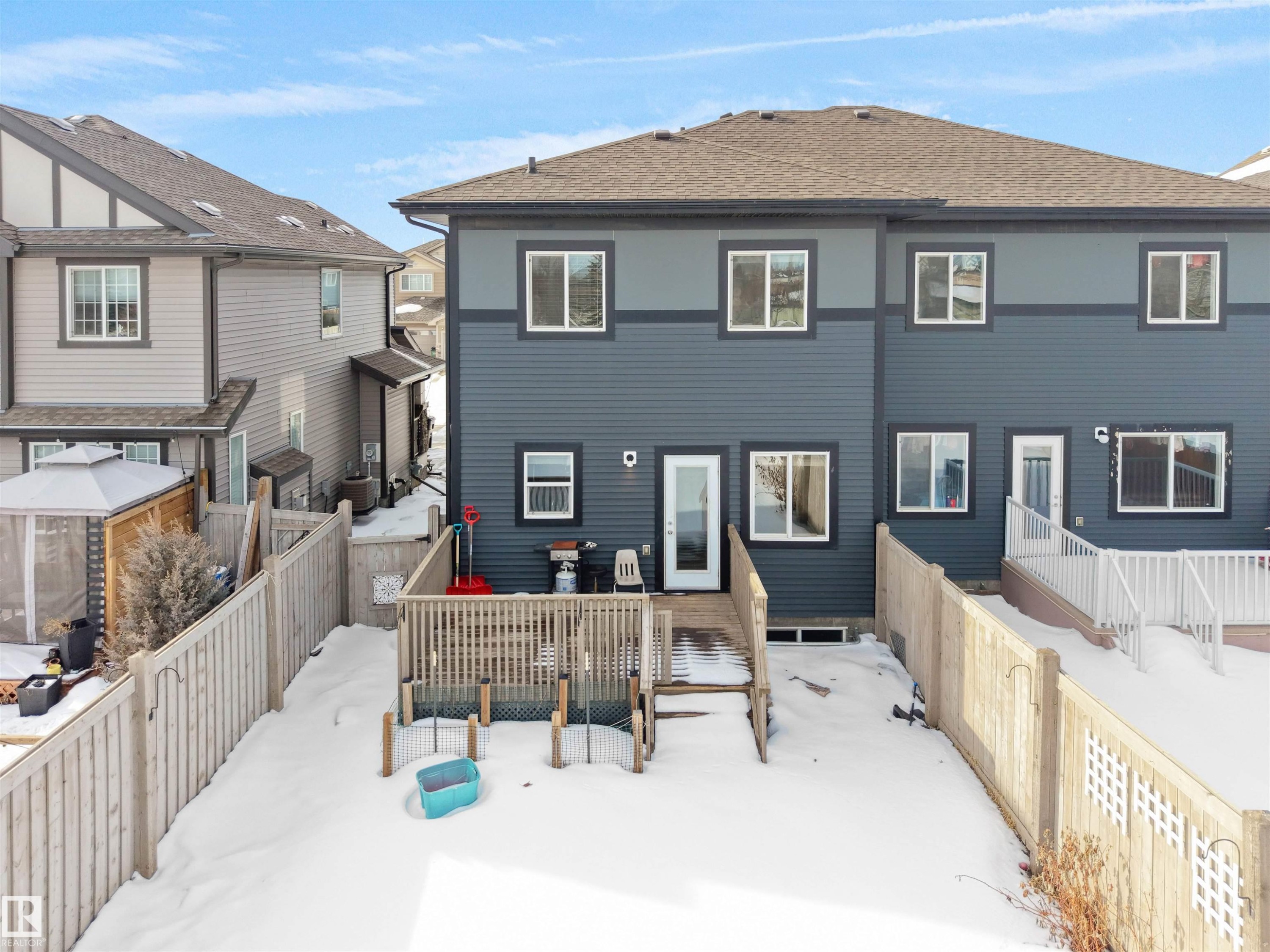 Rear exterior featuring dark blue horizontal siding and a brown shingle roof - 8921 217 Street Nw, Edmonton, AB - Outdoor With Deck Patio Veranda