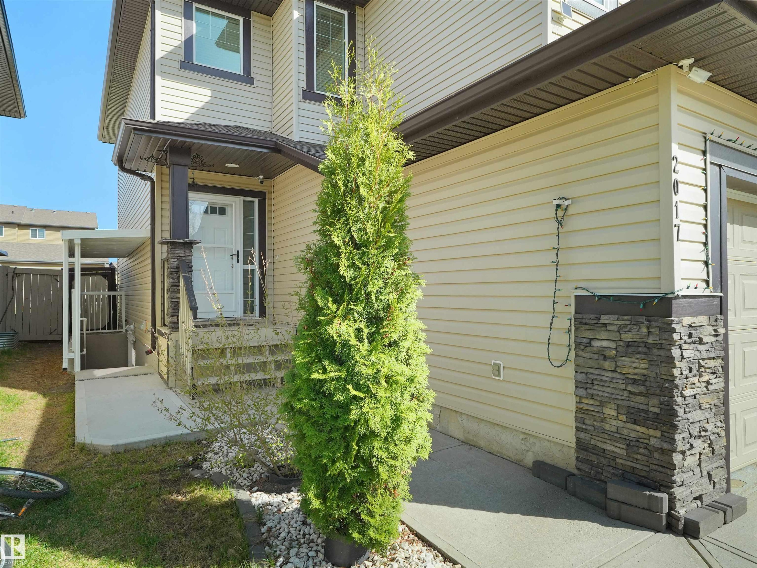 Two-story beige siding exterior with dark trim accents and stacked stone detailing - 2017 32A Street, Edmonton, AB - Outdoor