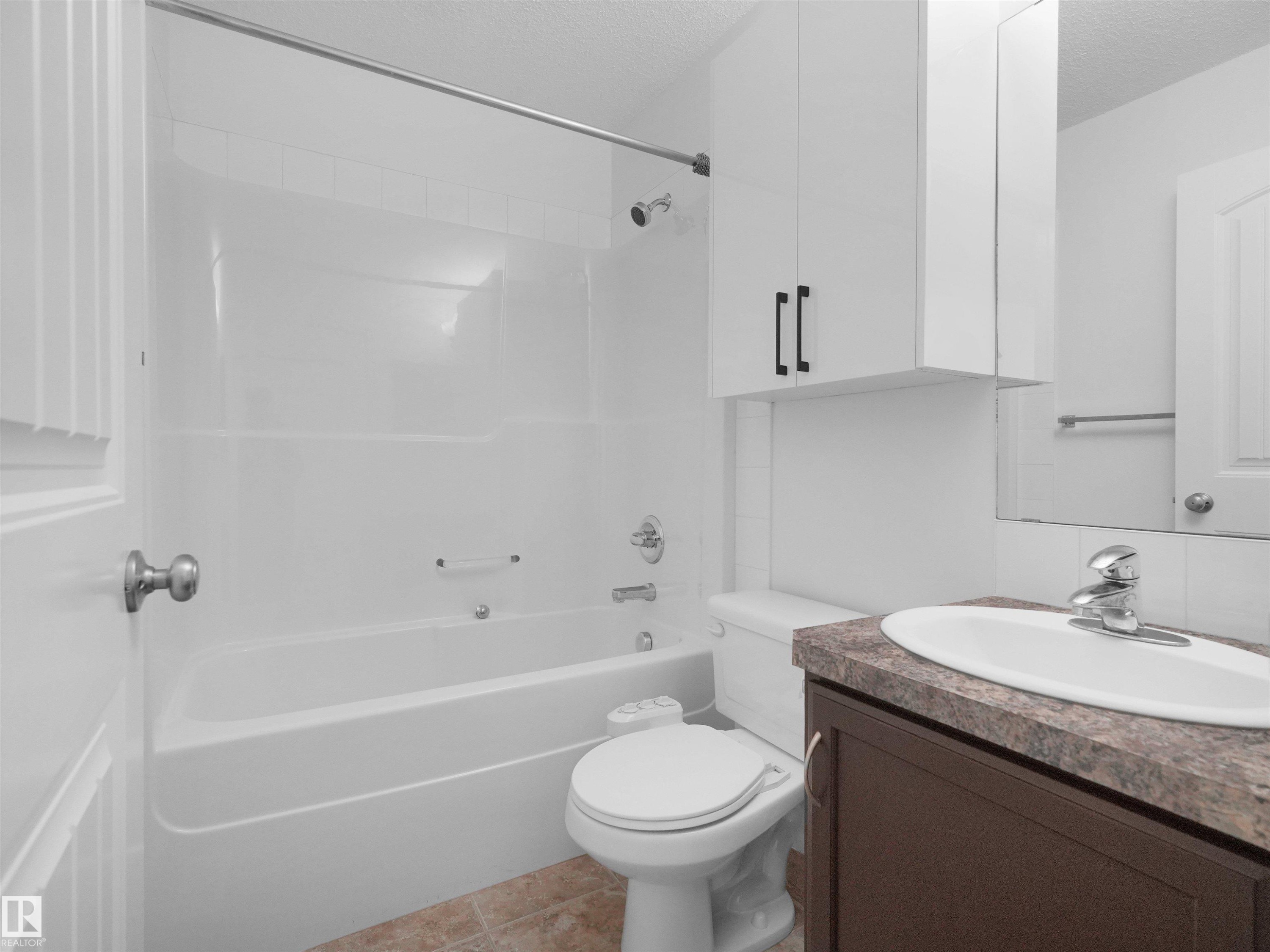 Bathroom featuring a white tub/shower combination, a dark wood-finish vanity with a built-in sink, and a mirrored medicine cabinet above - 2017 32A Street, Edmonton, AB - Indoor Photo Showing Bathroom
