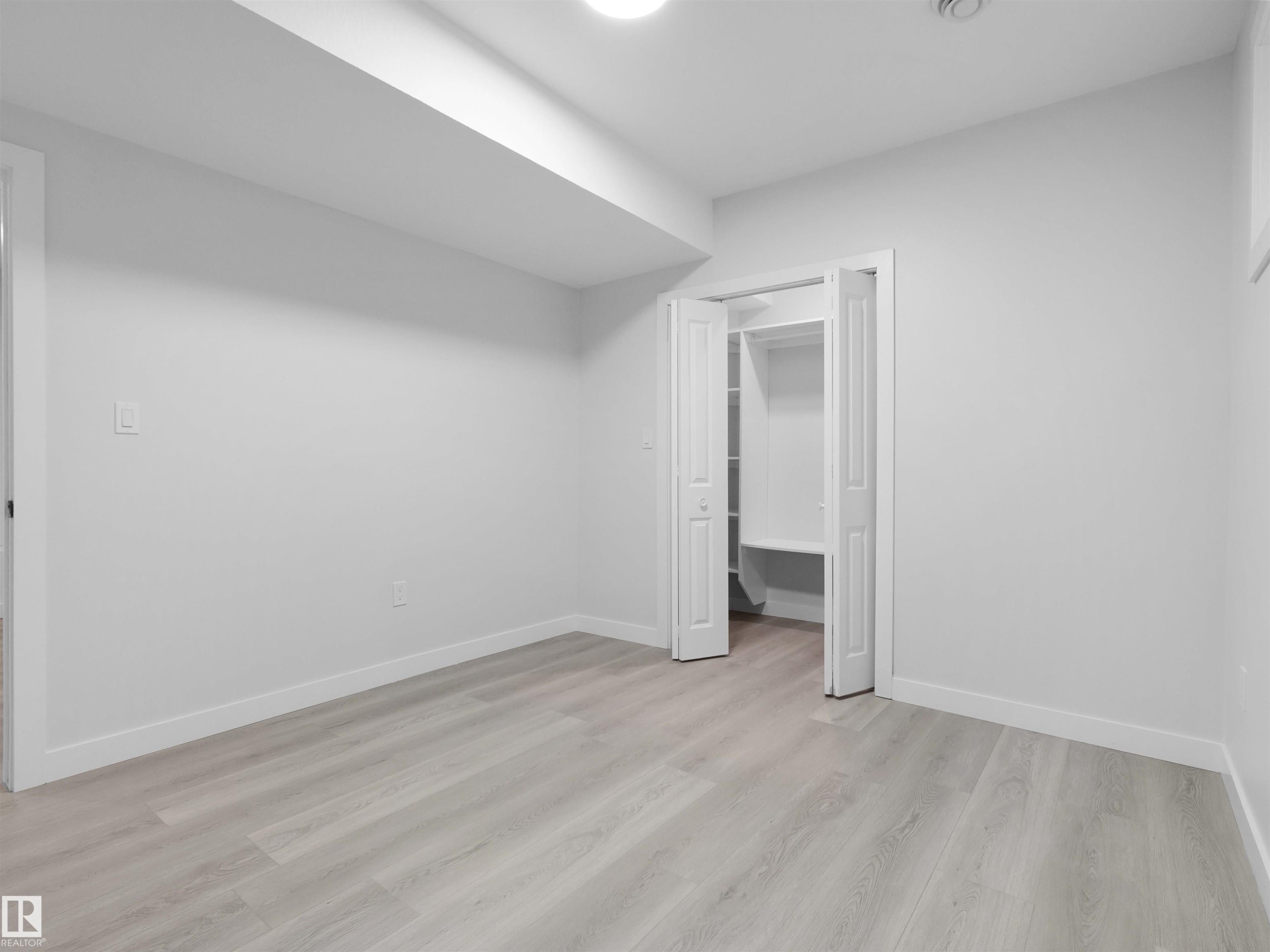 Spacious room featuring light wood-finish flooring, white walls, and bright baseboards - 2017 32A Street, Edmonton, AB - Indoor Photo Showing Other Room