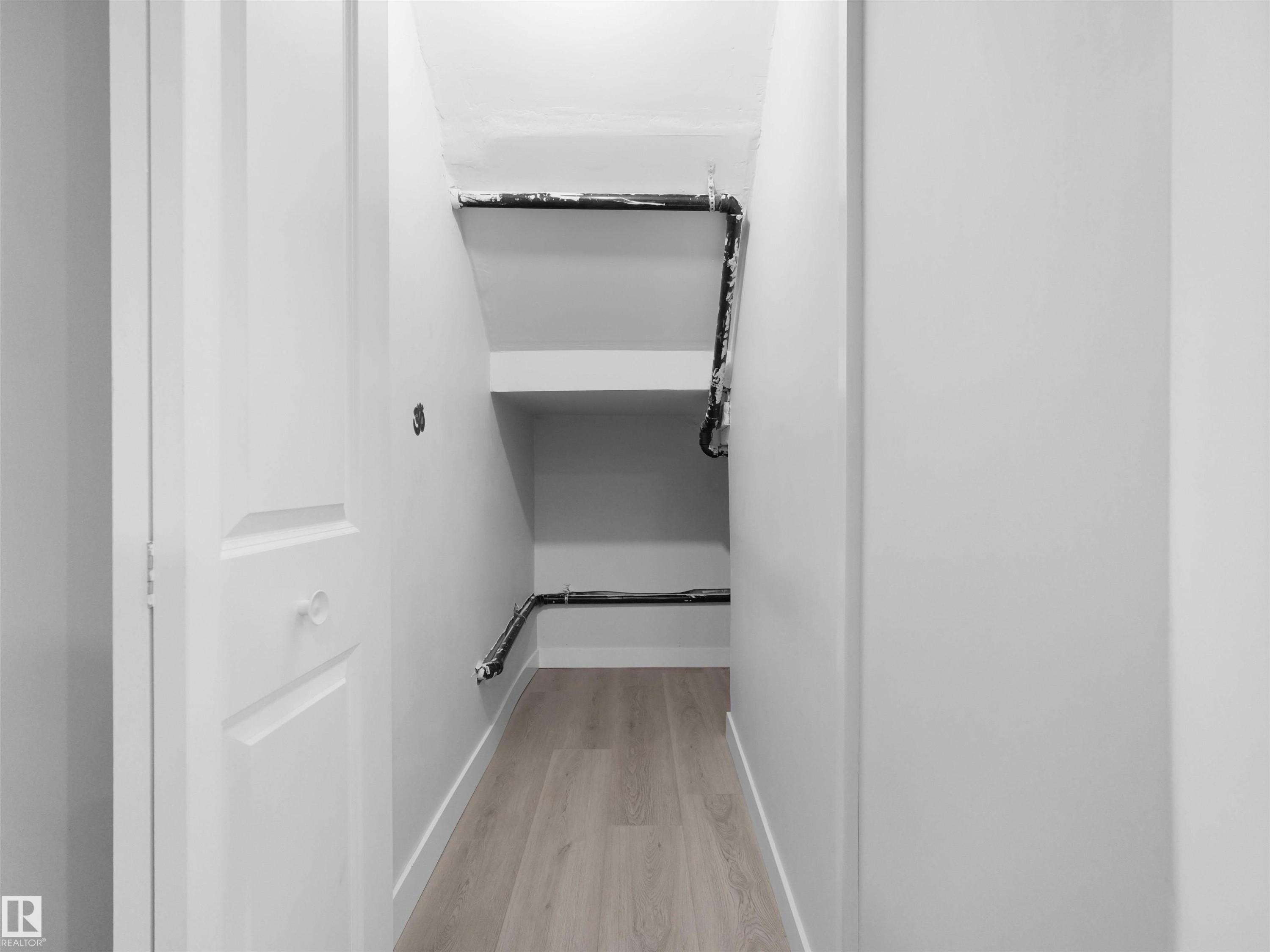 Under-stair storage area featuring integrated shelving, light wood-finish flooring, and crisp white walls - 2017 32A Street, Edmonton, AB - Indoor
