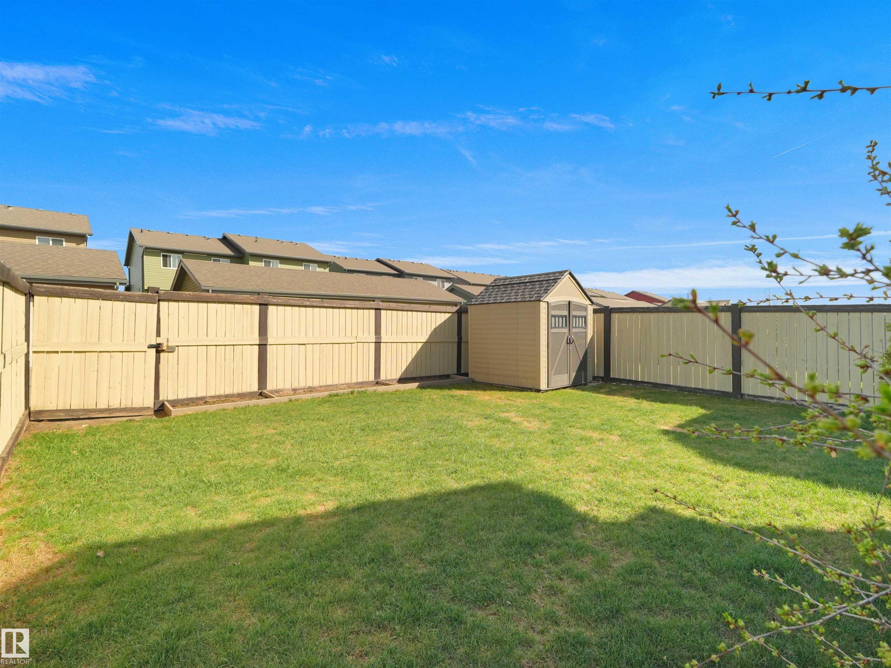Expansive fenced backyard featuring a manicured lawn, a detached storage shed, and a privacy fence - 2017 32A Street, Edmonton, AB - Outdoor