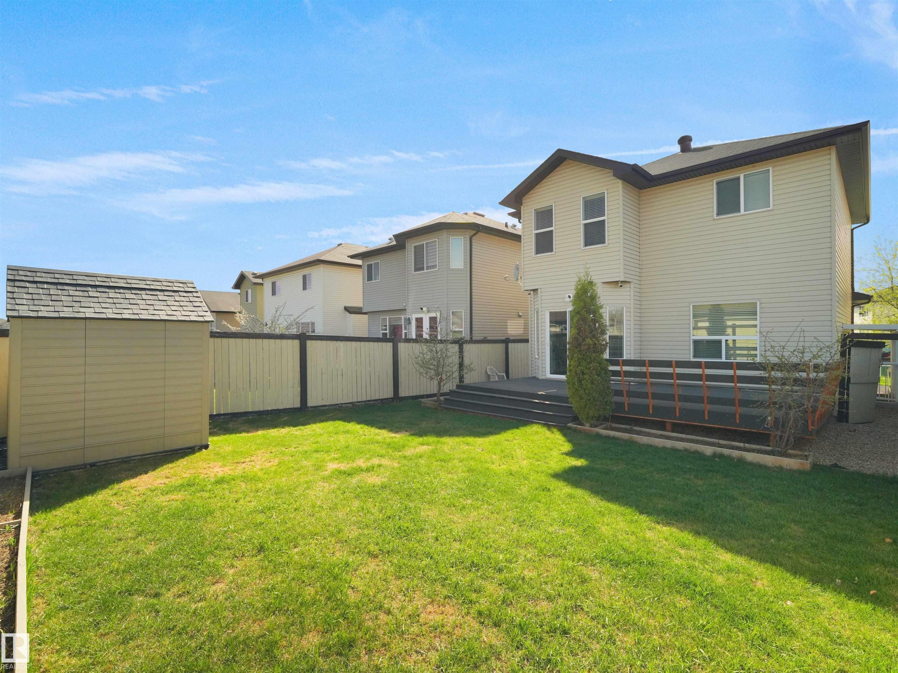 Expansive backyard featuring a manicured lawn, a detached storage shed, a multi-level deck, and a privacy fence - 2017 32A Street, Edmonton, AB - Outdoor