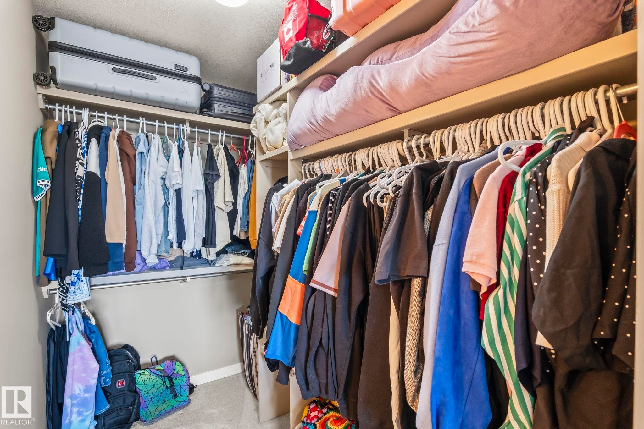 Built-in closet organization system featuring multiple hanging rods and shelving - 412 5005 165 Avenue Nw, Edmonton, AB - Indoor With Storage
