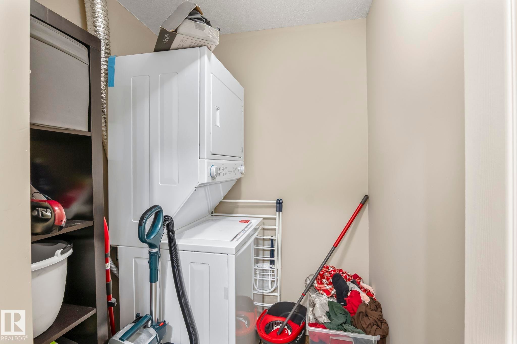 Dedicated laundry area featuring a stacked washer and dryer unit - 412 5005 165 Avenue Nw, Edmonton, AB - Indoor Photo Showing Laundry Room