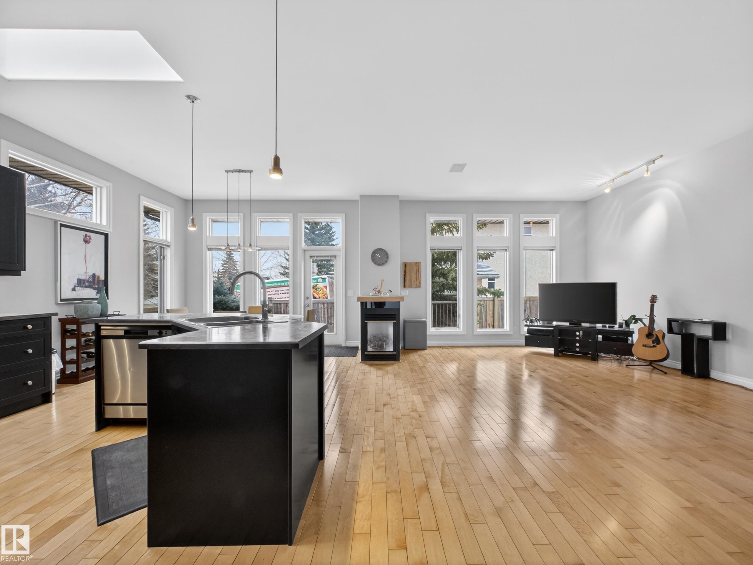 Open-concept living space featuring wood-finish flooring and ample natural light from multiple windows - 569 Butterworth Way, Edmonton, AB - Indoor