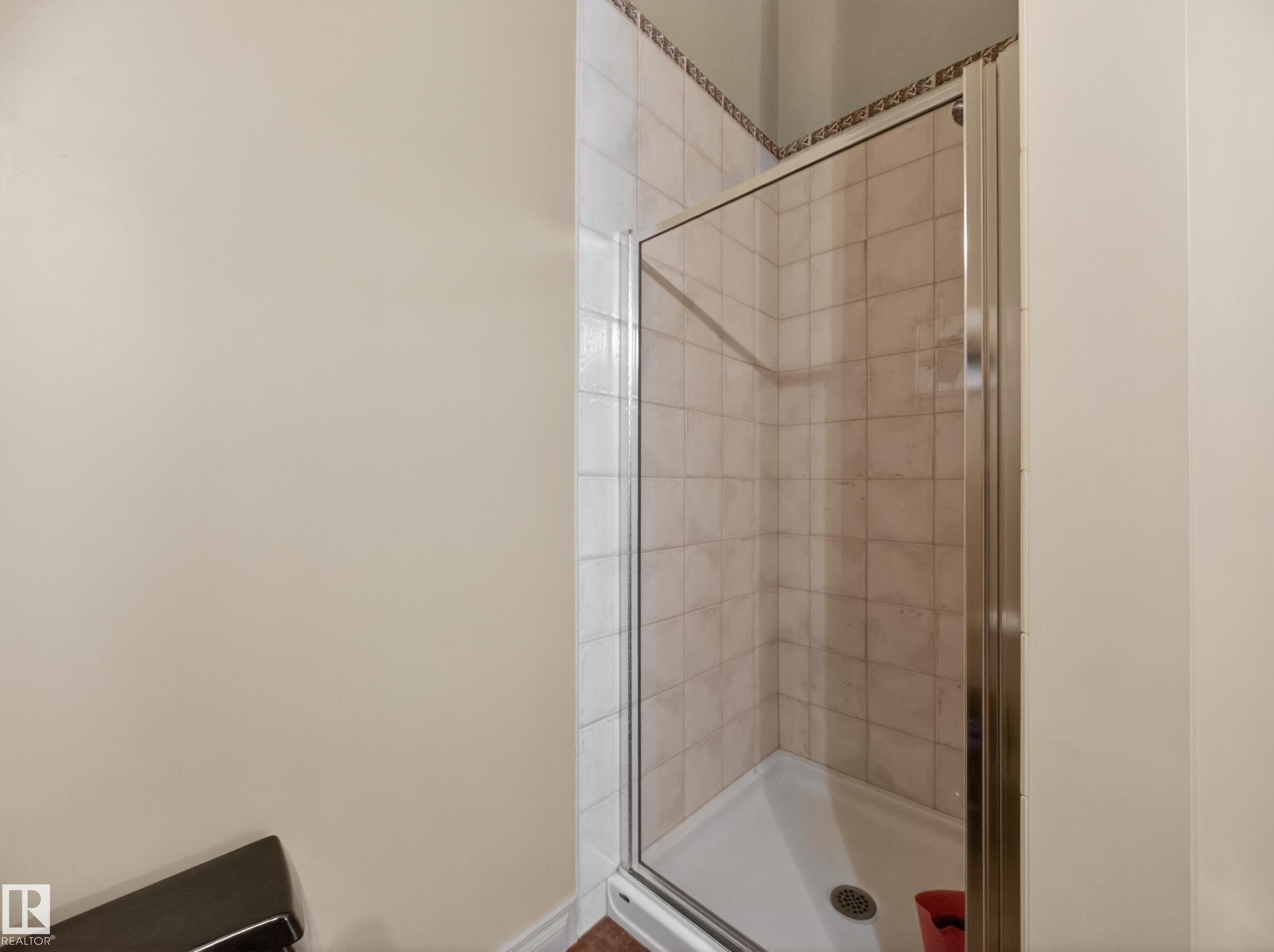 Enclosed shower stall featuring tiled walls with a decorative border and a white shower base - 569 Butterworth Way, Edmonton, AB - Indoor Photo Showing Bathroom