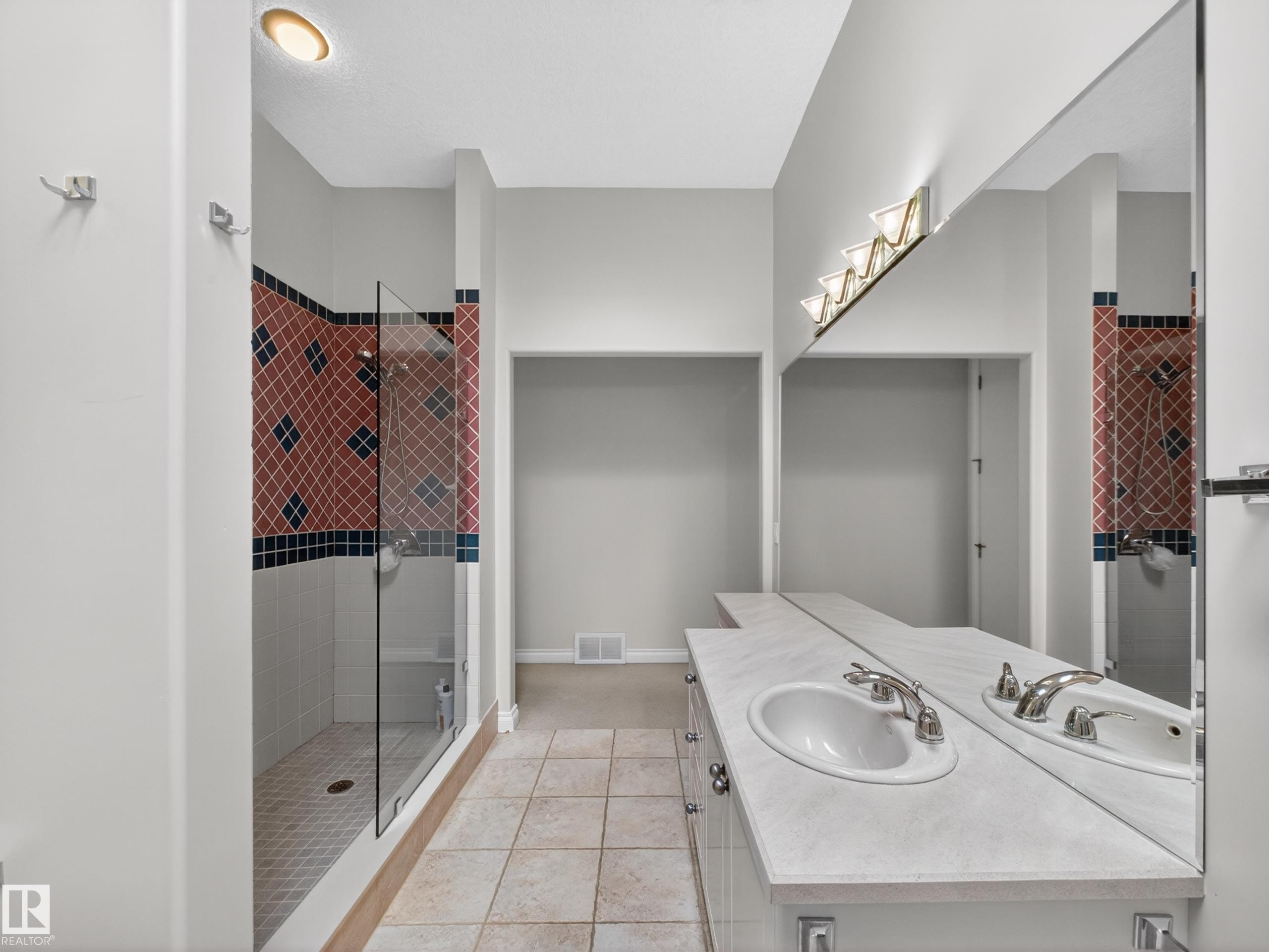 Spacious bathroom featuring a glass-enclosed shower with patterned tile, dual vanity with integrated sinks, and ample counter space - 569 Butterworth Way, Edmonton, AB - Indoor Photo Showing Bathroom