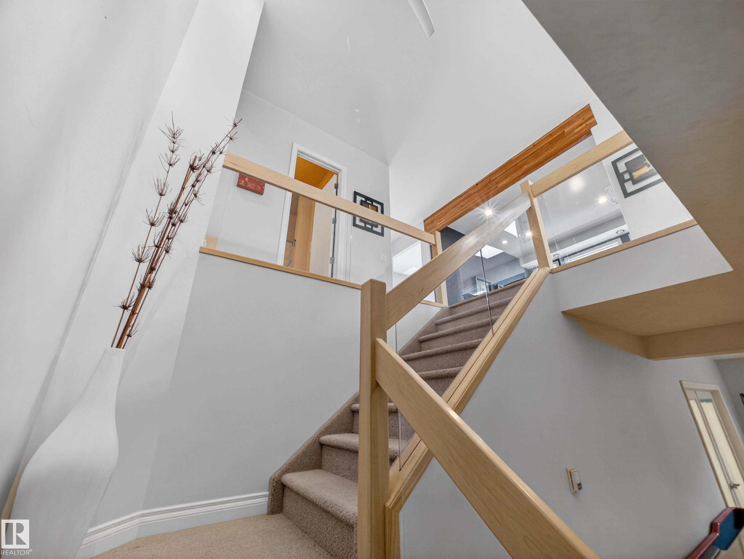 Multi-level staircase featuring light wood railings, clear glass panels, and carpeted treads - 569 Butterworth Way, Edmonton, AB - Indoor Photo Showing Other Room