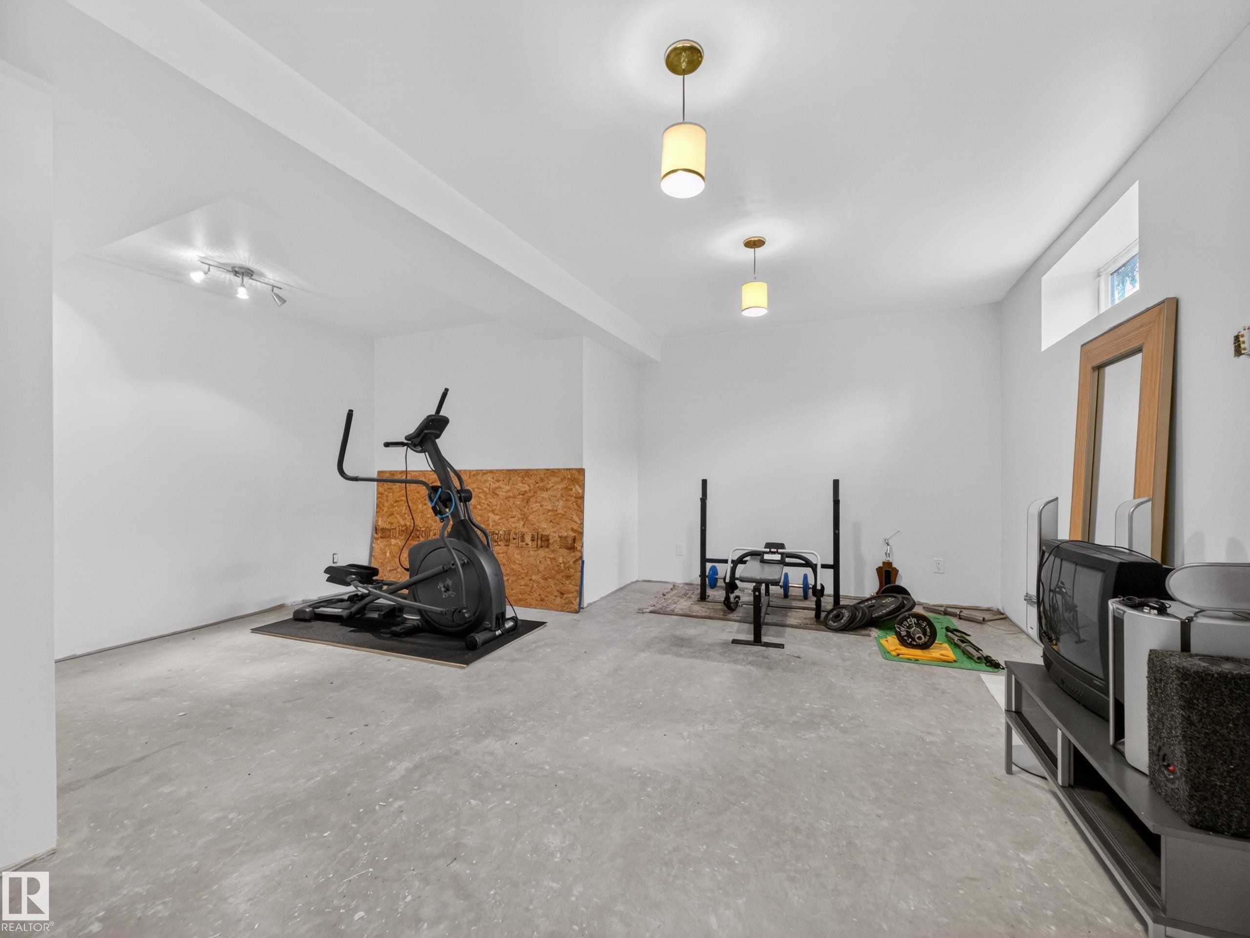 Spacious lower level featuring painted walls, concrete flooring, and ceiling-mounted light fixtures - 569 Butterworth Way, Edmonton, AB - Indoor