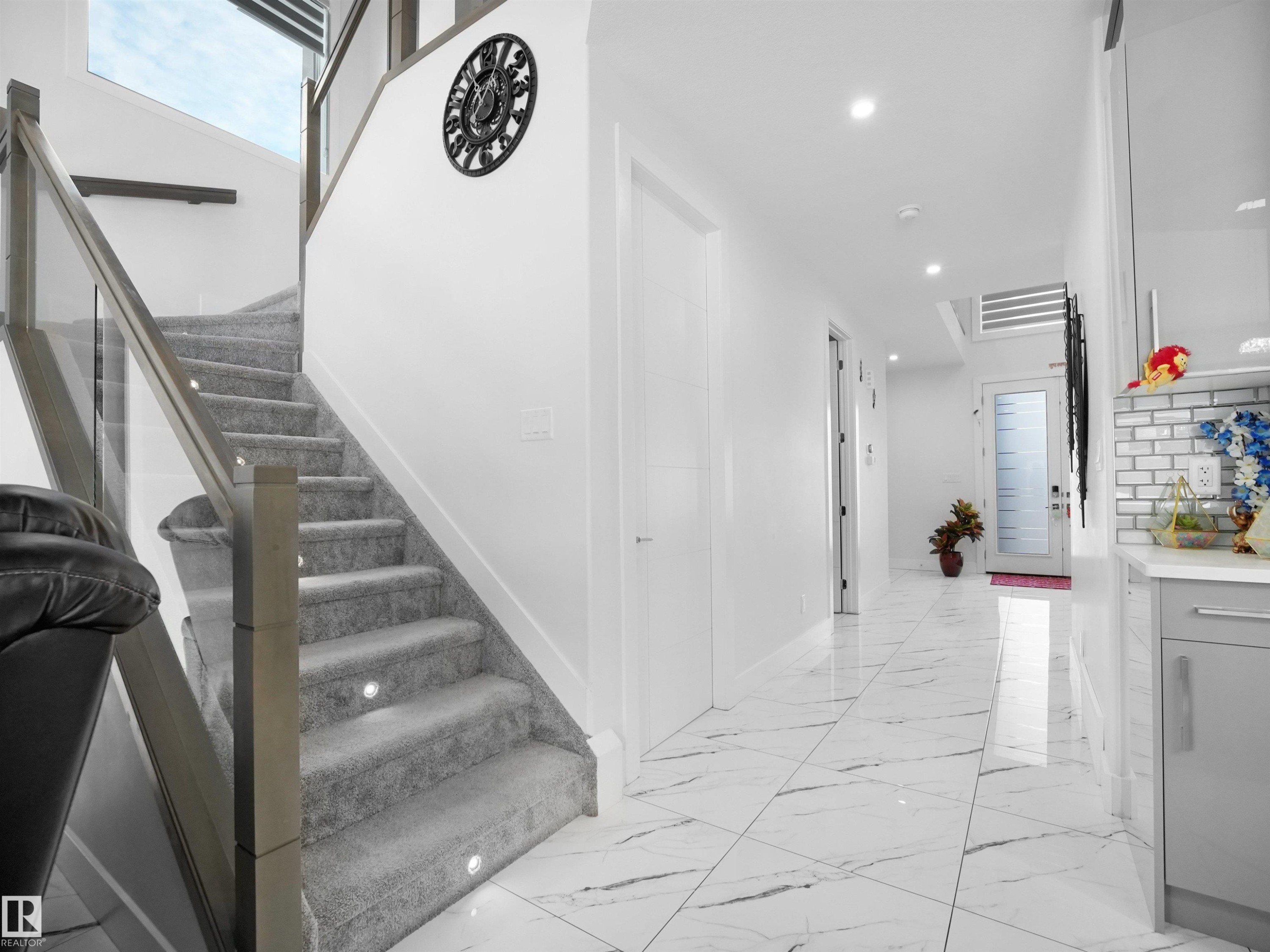 Staircase with glass railing, carpeted treads, and integrated step lighting - 1208 25 St Nw, Edmonton, AB - Indoor Photo Showing Other Room