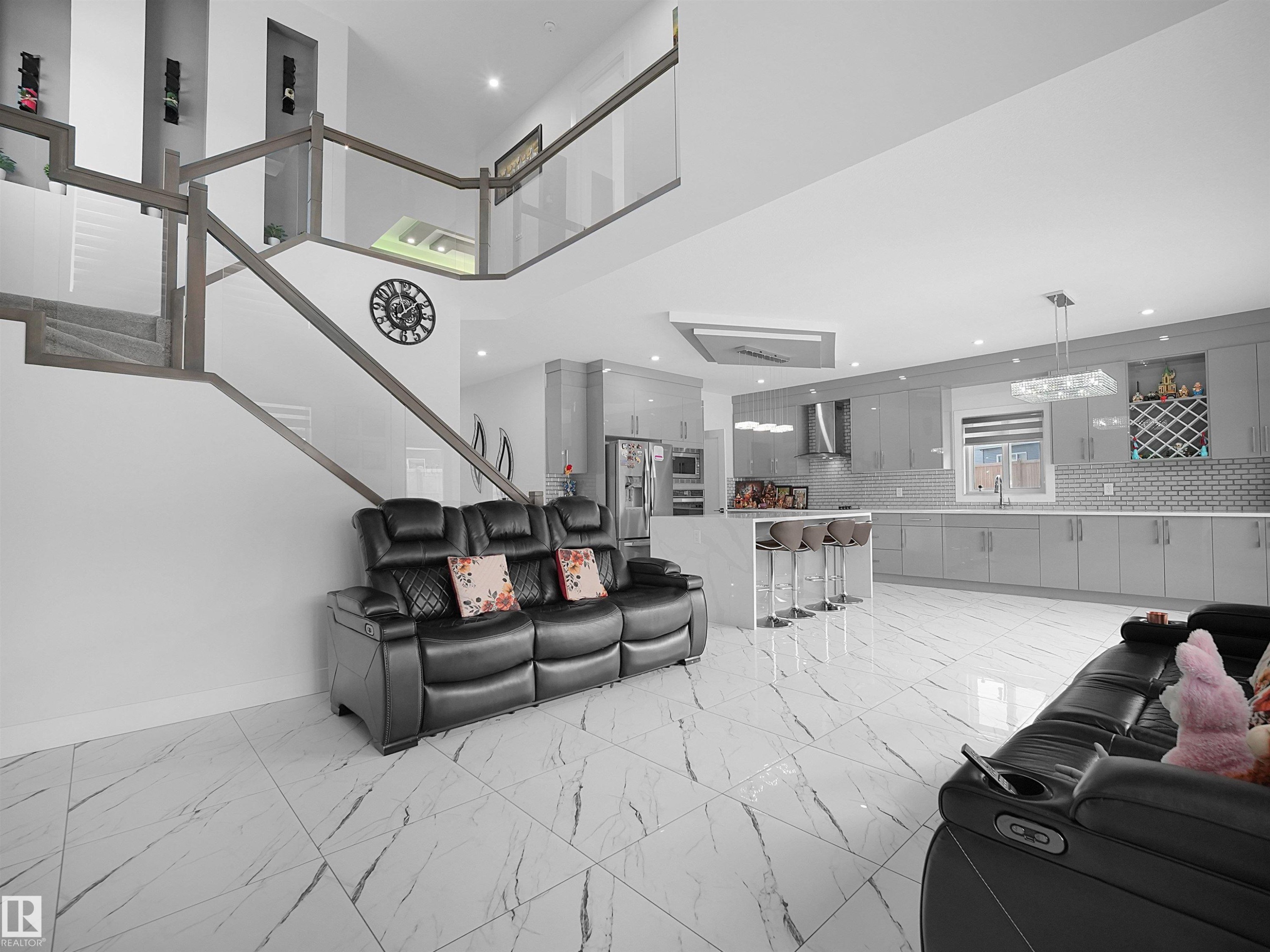 Open-concept living space featuring a contemporary kitchen with gray cabinetry, a central island with bar seating, and white tile flooring - 1208 25 St Nw, Edmonton, AB - Indoor