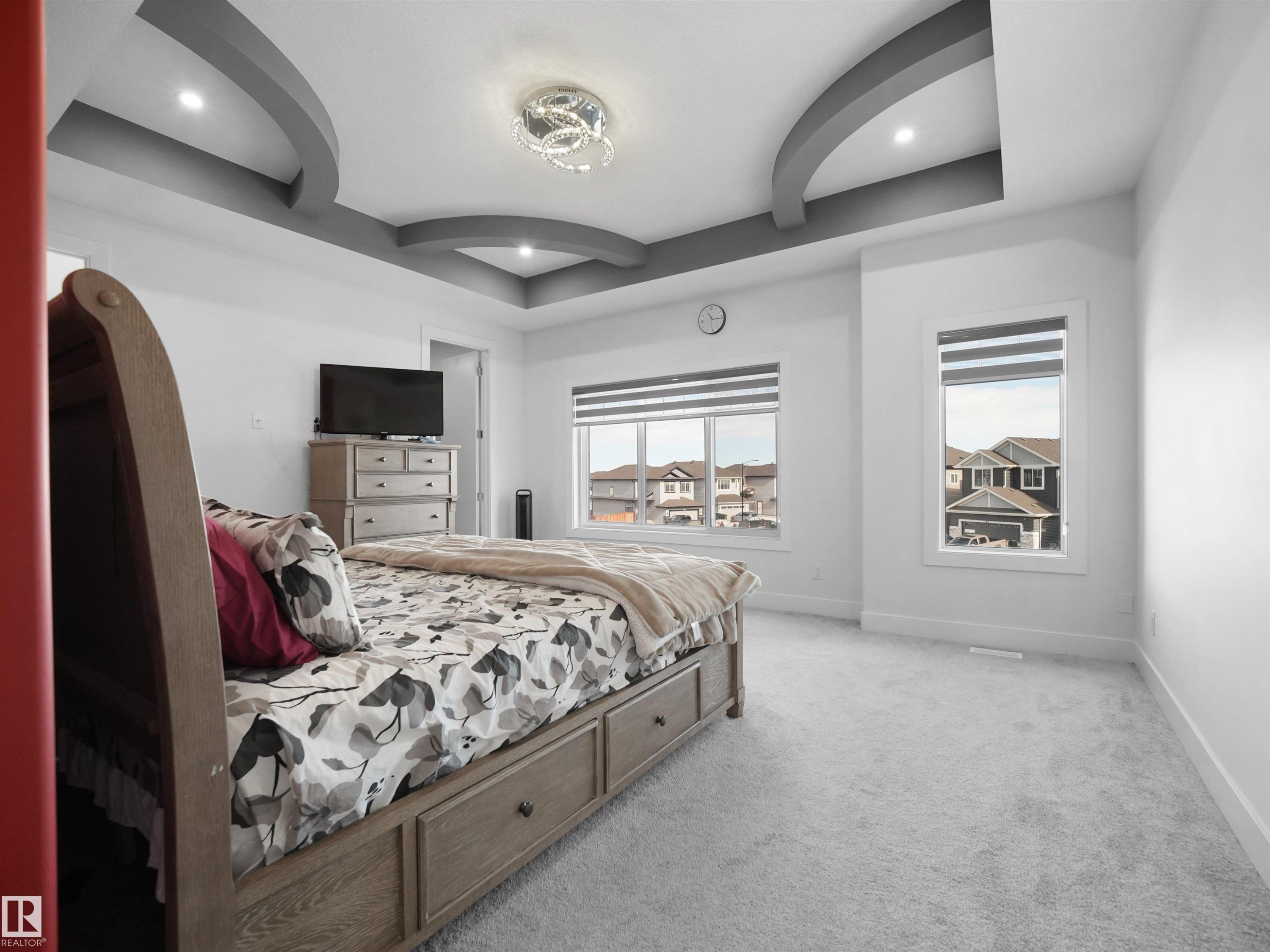 Spacious room featuring a decorative tray ceiling with recessed lighting and a central chandelier - 1208 25 St Nw, Edmonton, AB - Indoor Photo Showing Bedroom