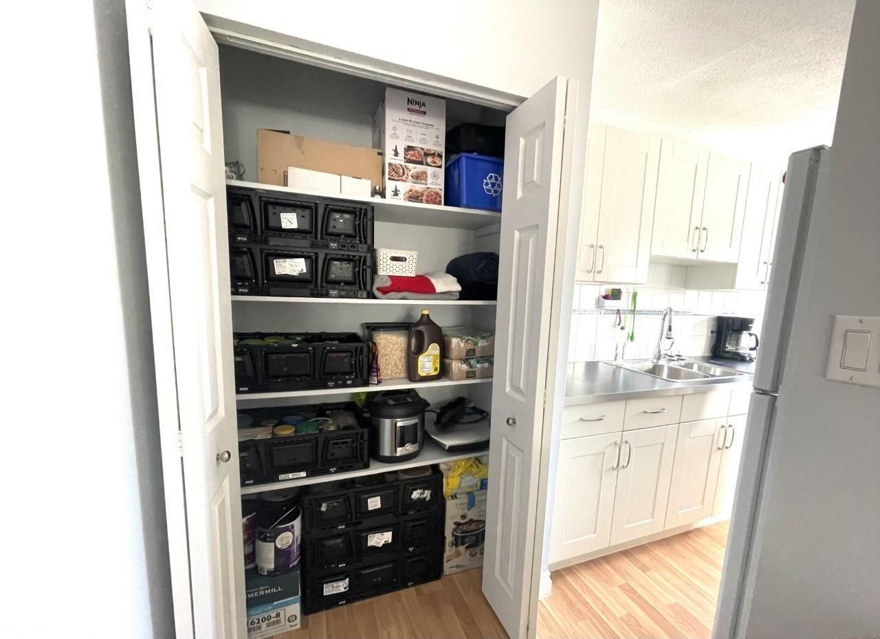 Kitchen pantry with bi-fold doors offering multiple shelves for storage - #303 12223 82 St Nw, Edmonton, AB - Indoor