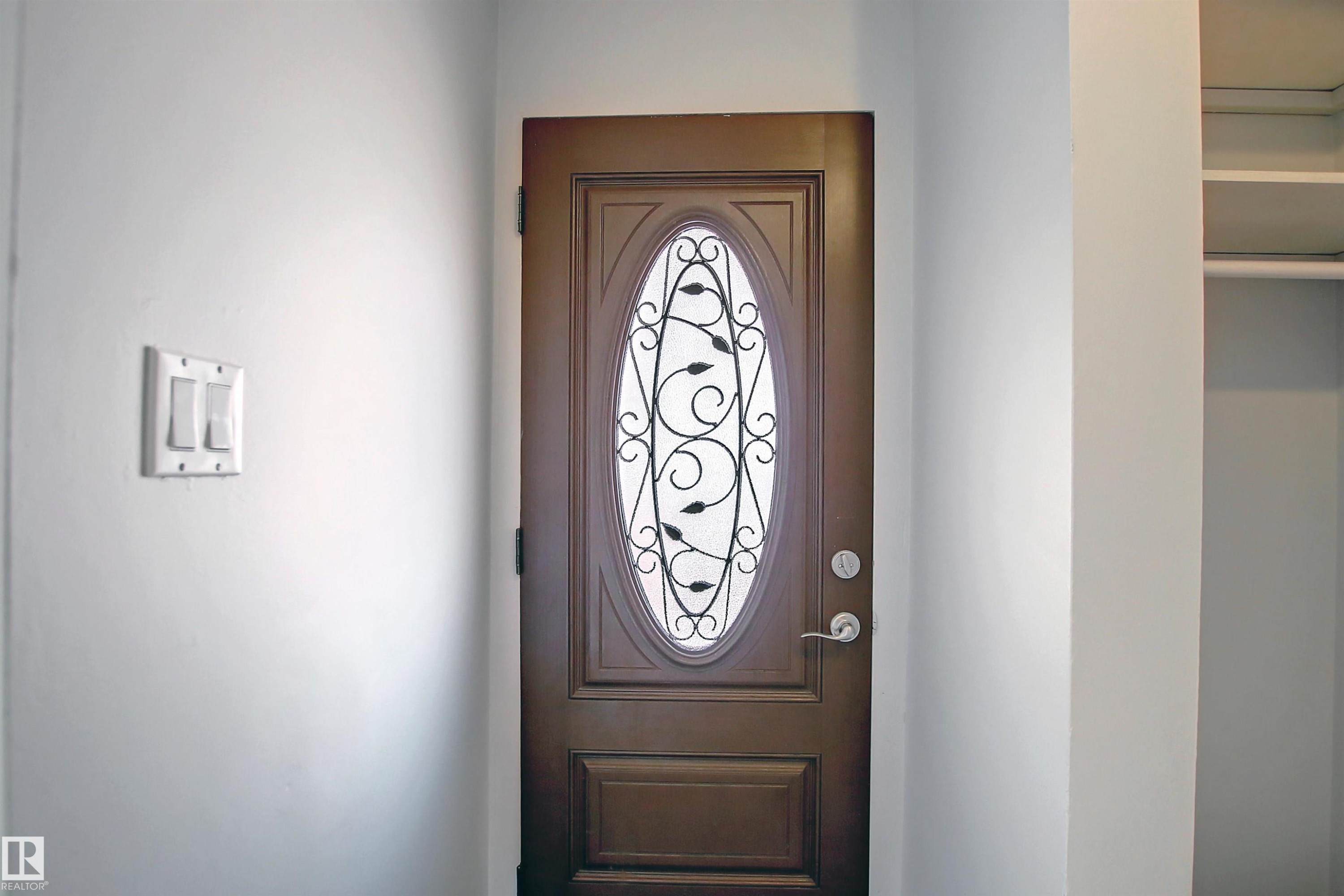 Oval-paneled entry door with decorative ironwork - 11 14120 80 Street, Edmonton, AB - Indoor Photo Showing Other Room