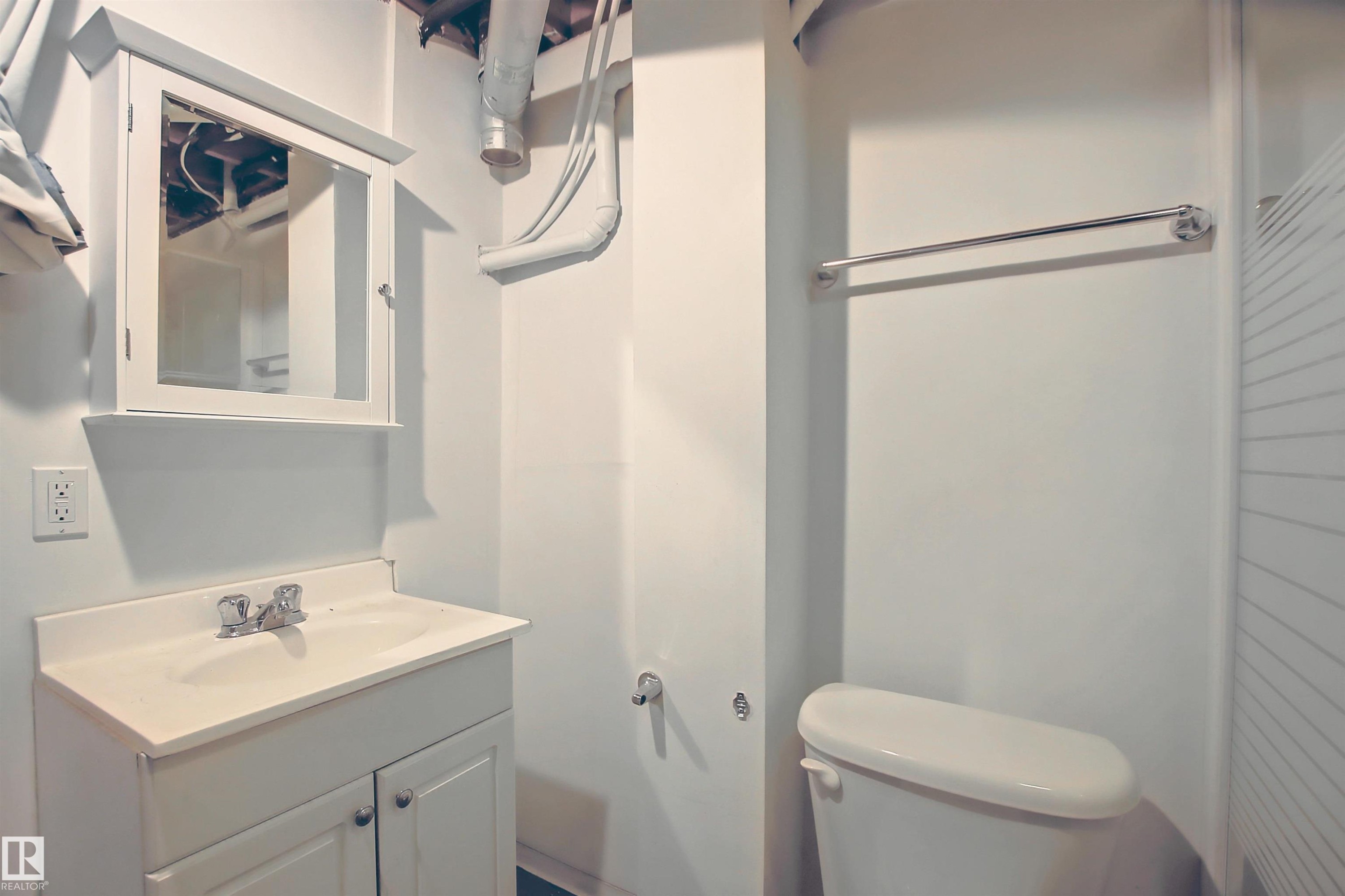 Bathroom featuring a white vanity with integrated sink, chrome faucet, wall-mounted medicine cabinet, toilet, and towel bar - 11 14120 80 Street, Edmonton, AB - Indoor Photo Showing Bathroom