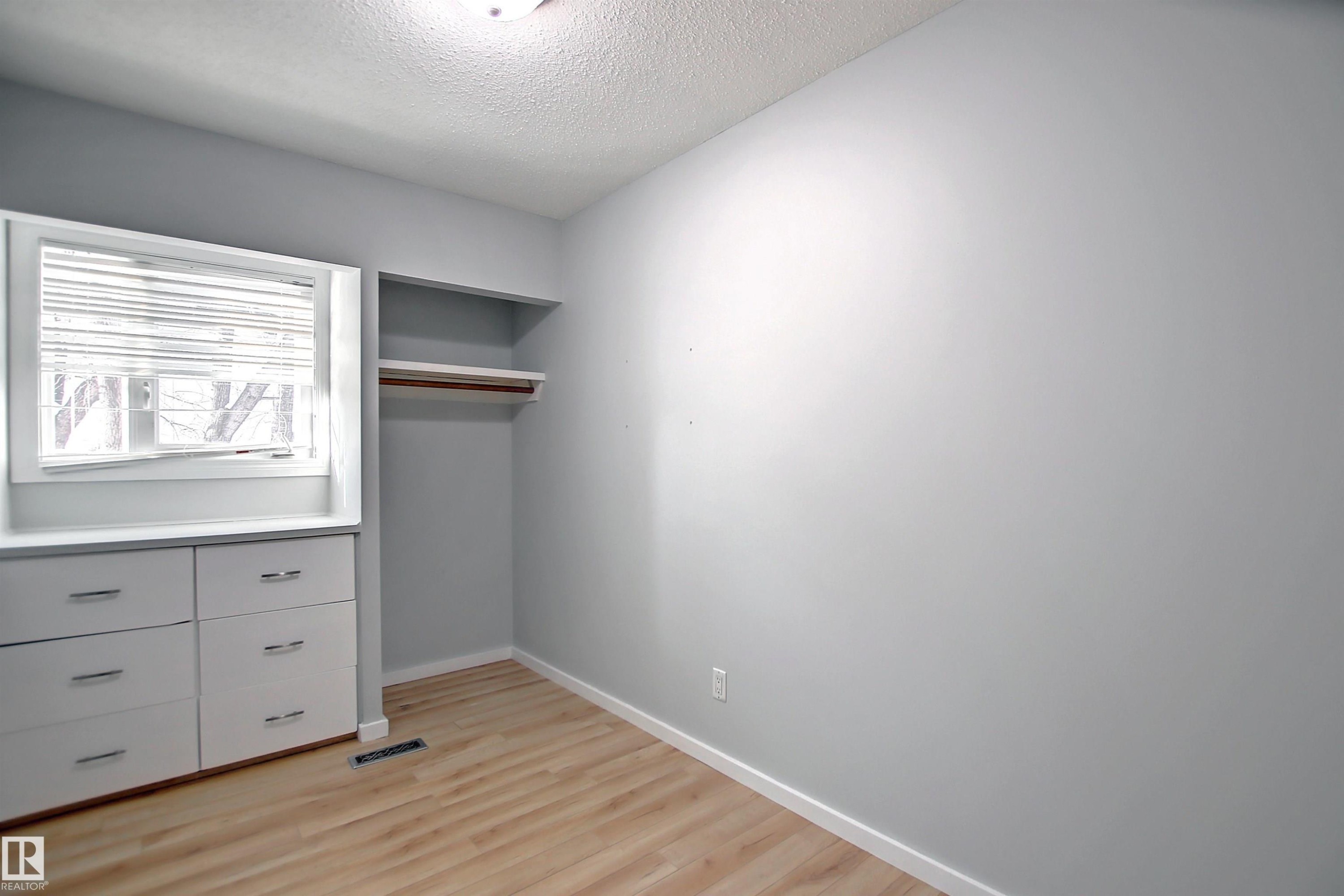 Room featuring wood-finish flooring, light grey walls, and a recessed window with blinds - 11 14120 80 Street, Edmonton, AB - Indoor Photo Showing Other Room