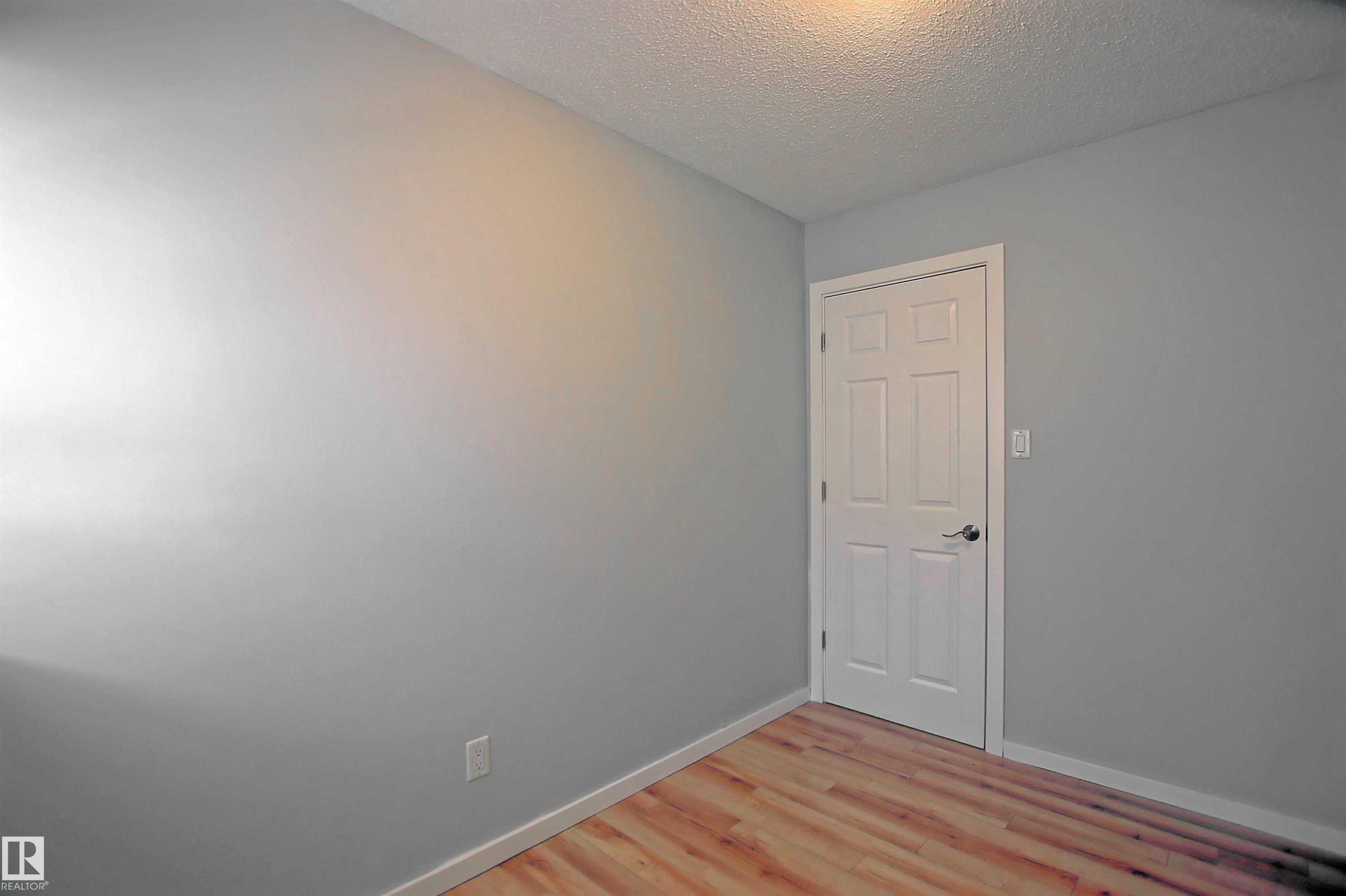 Light gray wall paint with white baseboards and wood-finish flooring - 11 14120 80 Street, Edmonton, AB - Indoor Photo Showing Other Room
