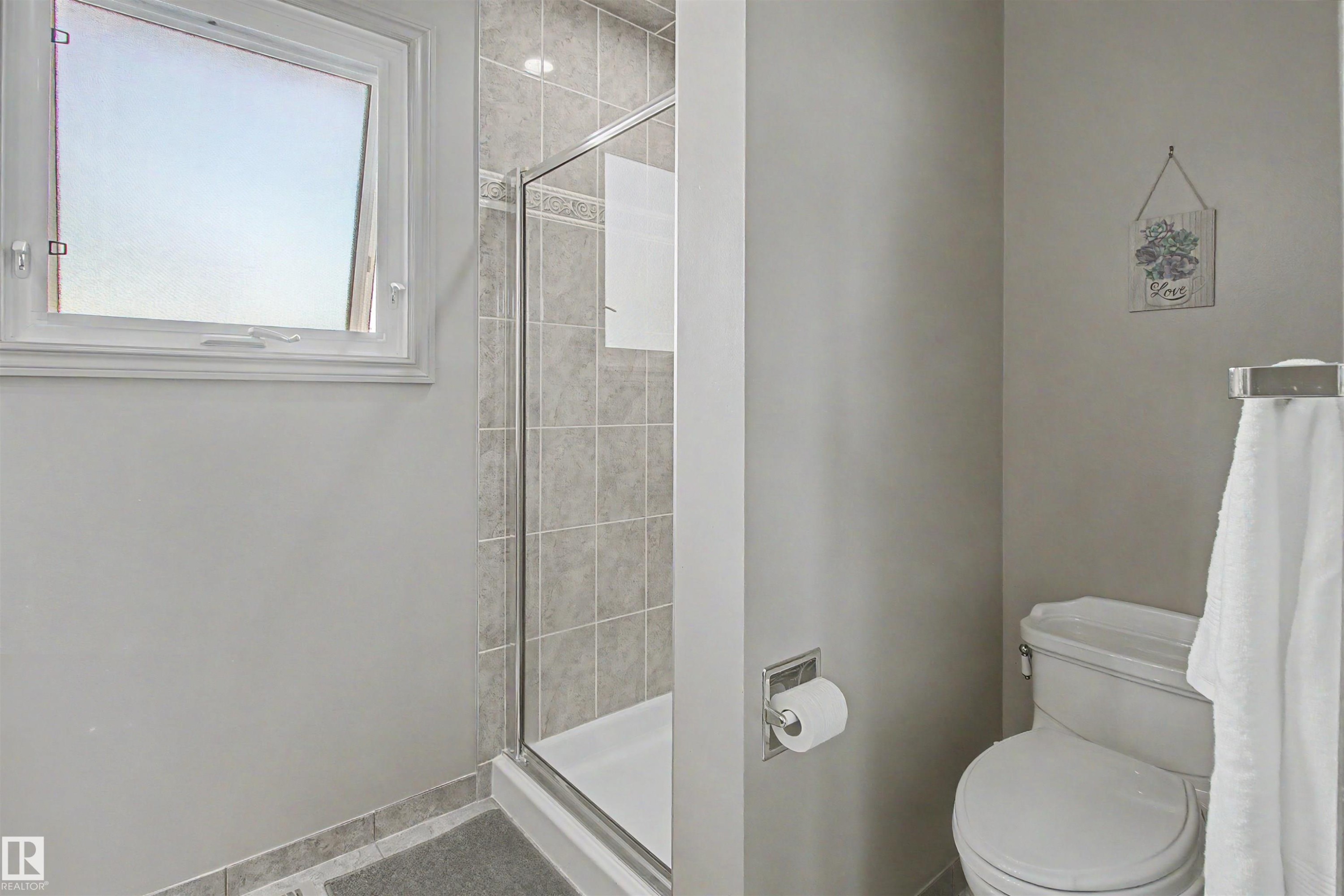 Shower enclosure with glass door, tile surround, and an integrated white shower pan - 11617 26 Avenue, Edmonton, AB - Indoor Photo Showing Bathroom