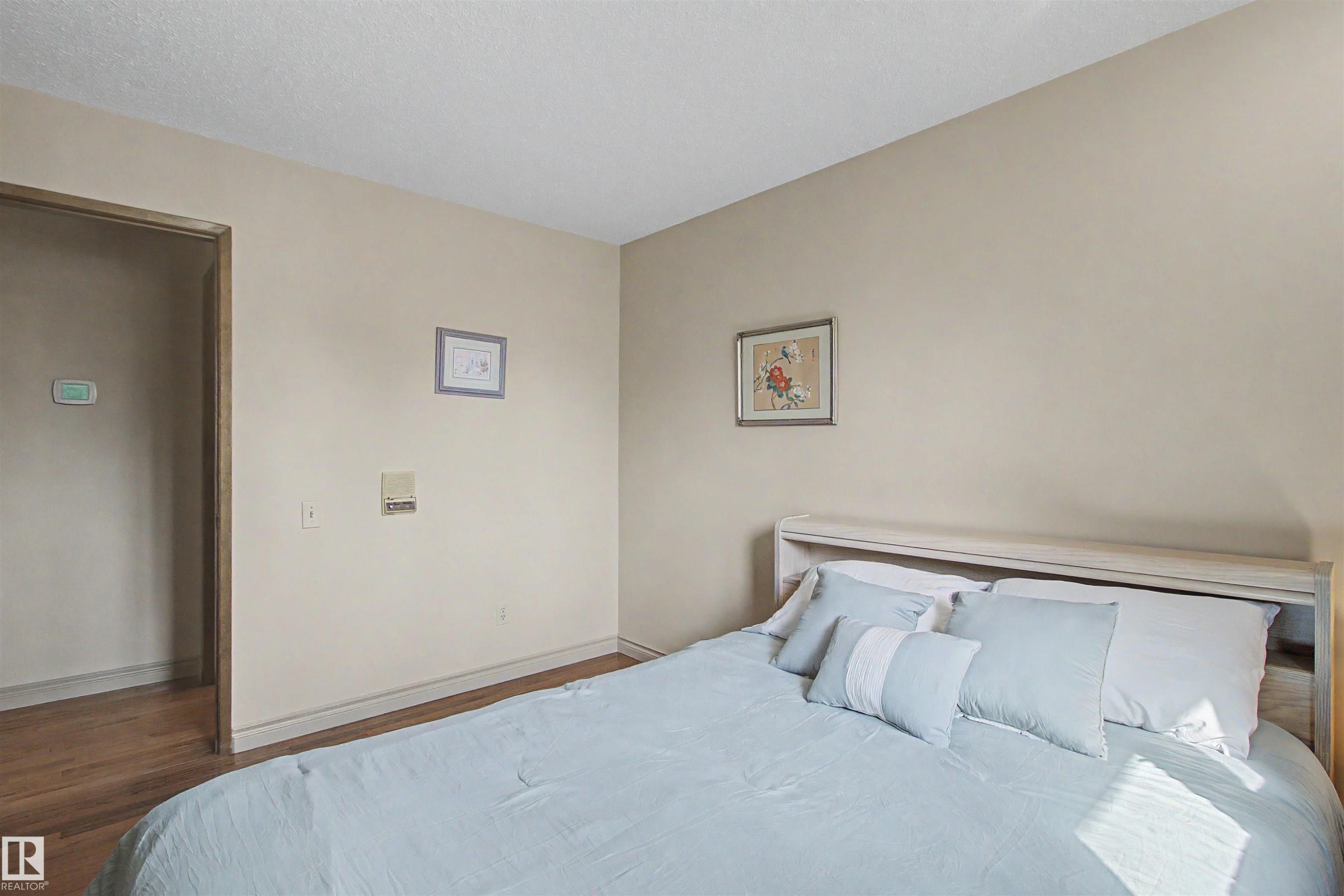 Bedroom featuring neutral wall paint, white baseboards, and wood-finish flooring extending into the hallway - 11617 26 Avenue, Edmonton, AB - Indoor Photo Showing Bedroom