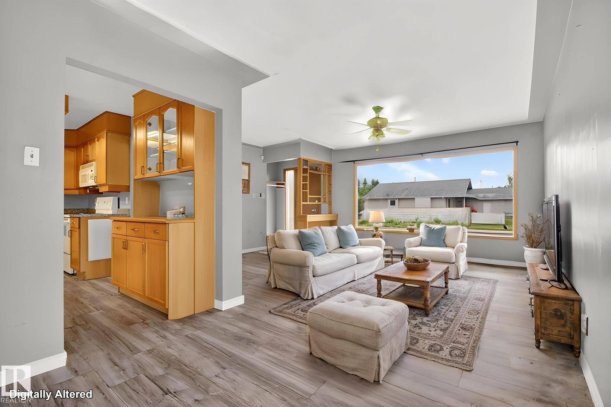 Living area featuring wood-finish flooring, a wide picture window, and a ceiling fan - 11901 42 Street Nw, Edmonton, AB - Indoor Photo Showing Living Room