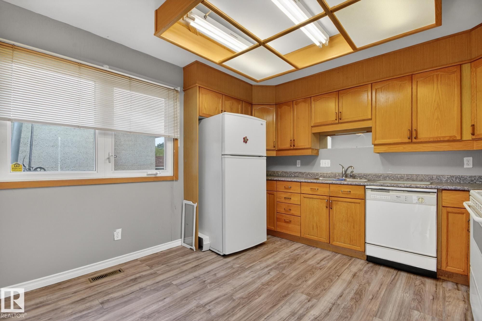 Kitchen featuring wood-finish cabinetry, white appliances, and a composite countertop - 11901 42 Street Nw, Edmonton, AB - Indoor Photo Showing Kitchen