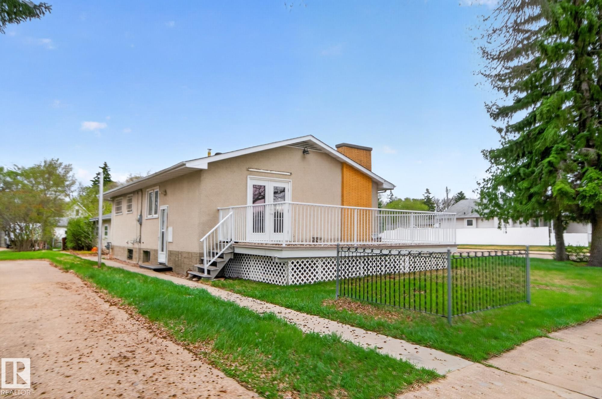 Rear elevation featuring a spacious composite deck with white railings, double glass pane doors, and a brick chimney - 11901 42 Street Nw, Edmonton, AB - Outdoor With Deck Patio Veranda