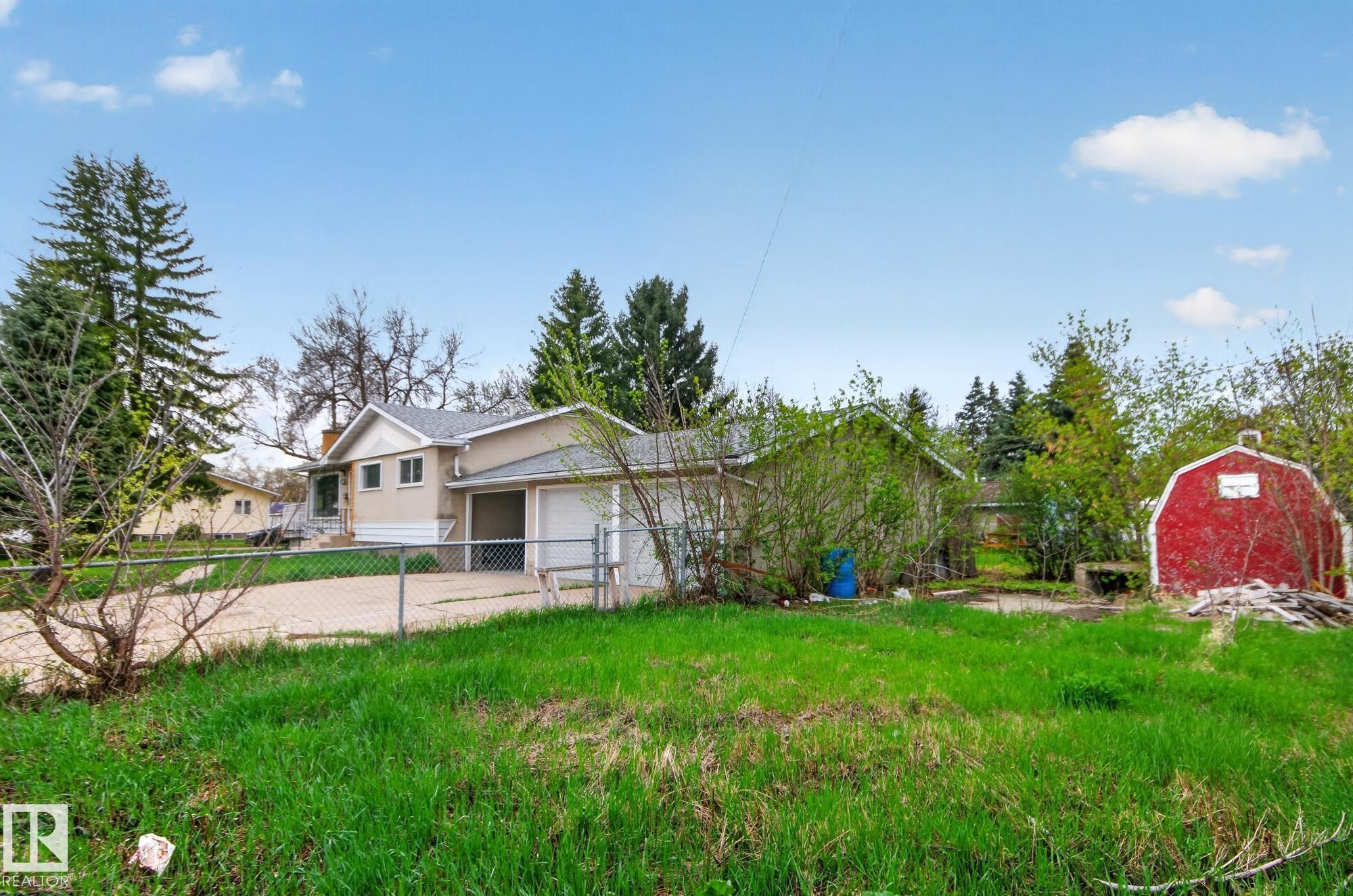 Exterior featuring a light-colored siding, attached garage, and a chain-link fence - 11901 42 Street Nw, Edmonton, AB - Outdoor