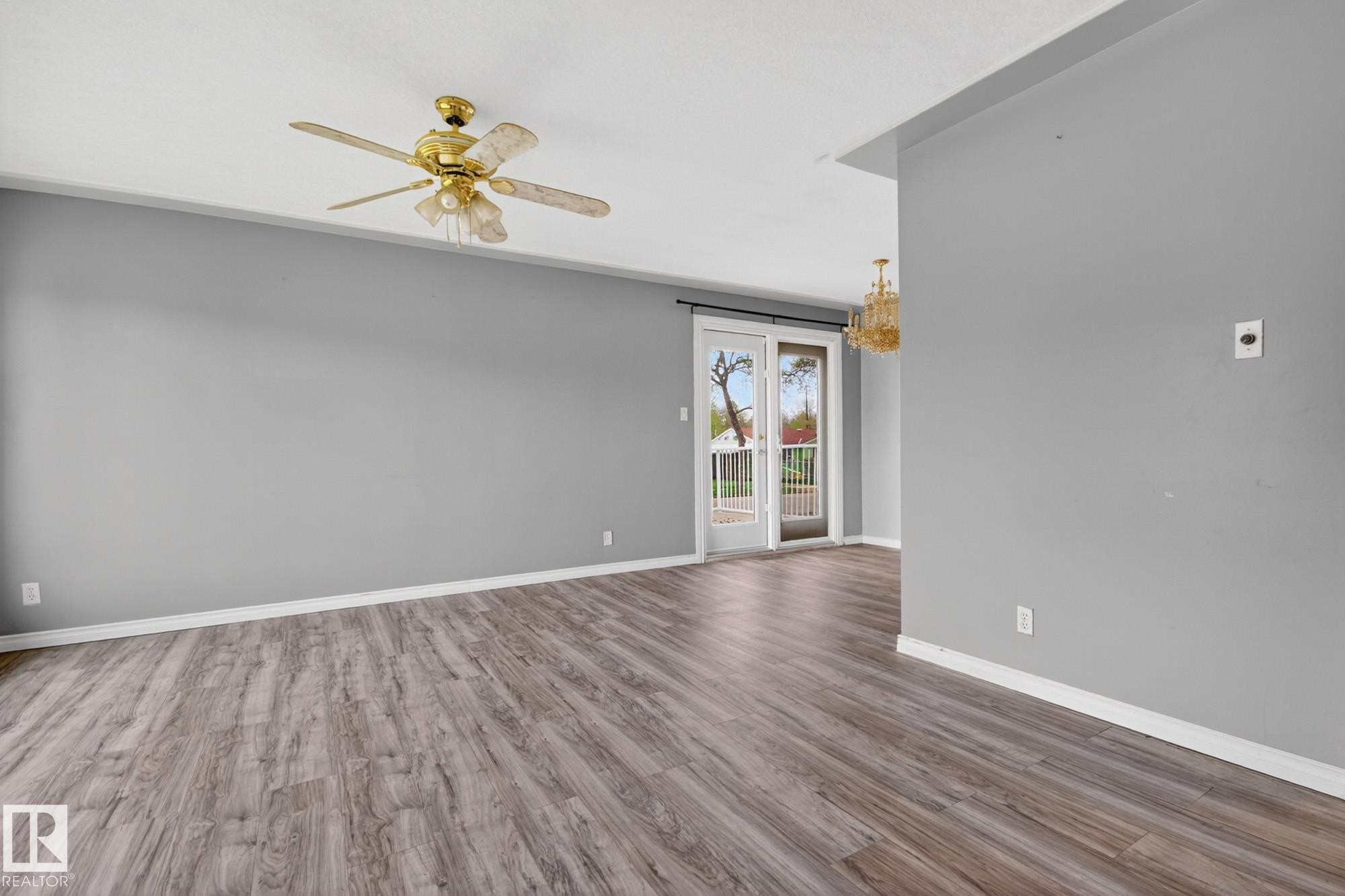 Spacious interior featuring wood-finish flooring, light grey walls, and white baseboards - 11901 42 Street Nw, Edmonton, AB - Indoor Photo Showing Other Room