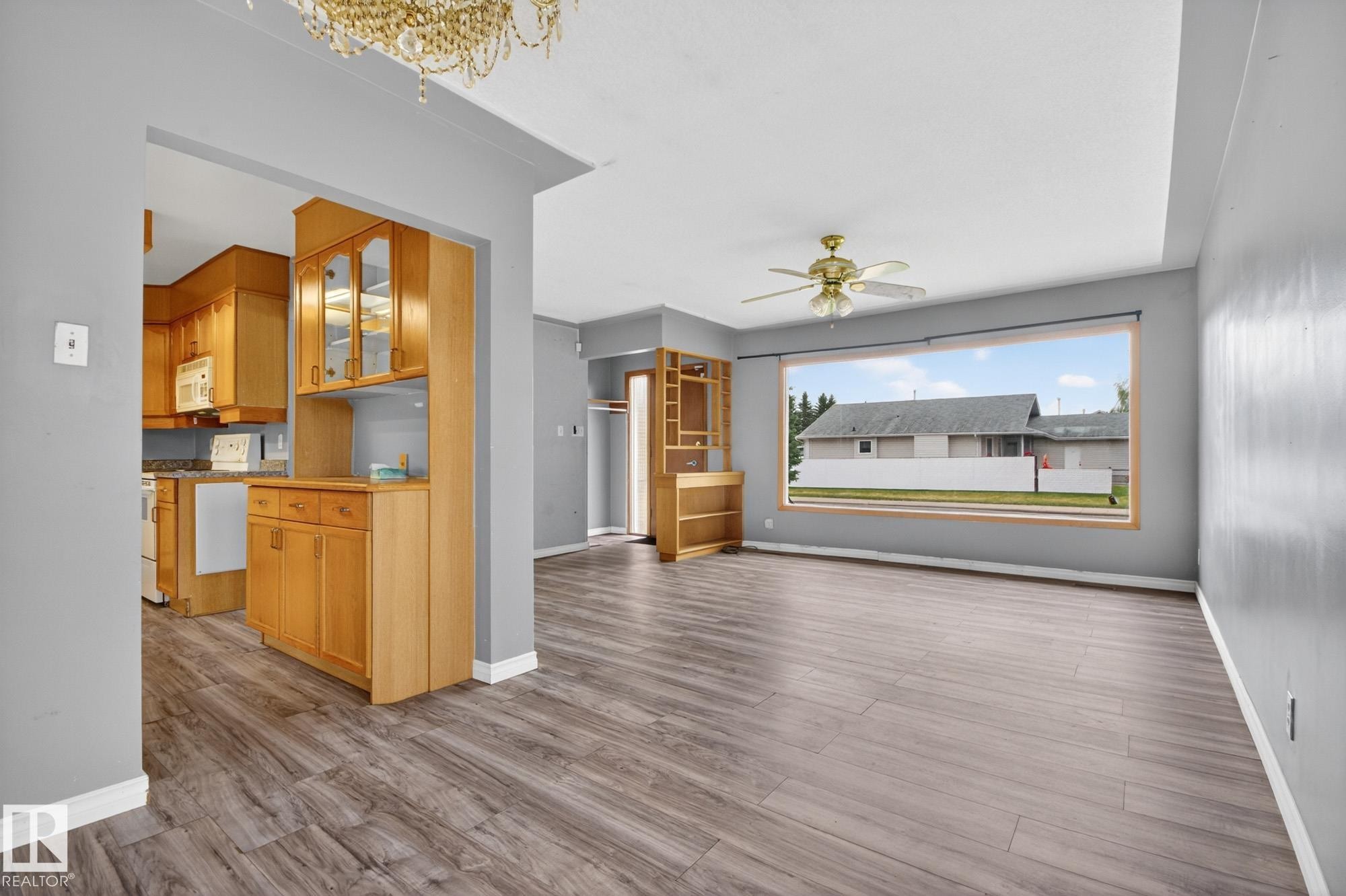 Spacious living area featuring wood-finish flooring, a large picture window, and a ceiling fan - 11901 42 Street Nw, Edmonton, AB - Indoor