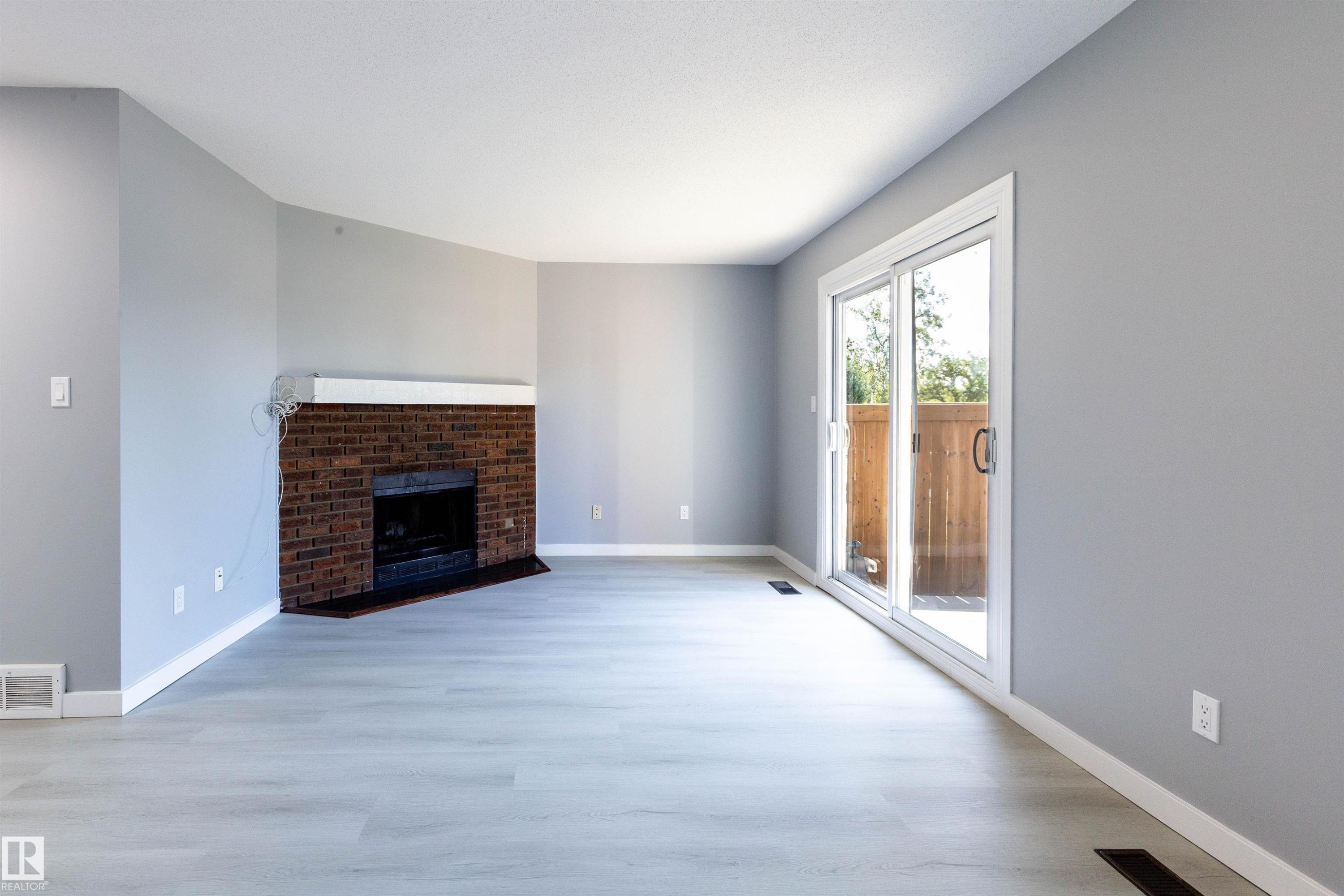 Spacious room featuring light gray walls, wood-finish flooring, and white baseboards - 547 Dunluce Road, Edmonton, AB - Indoor Photo Showing Living Room With Fireplace