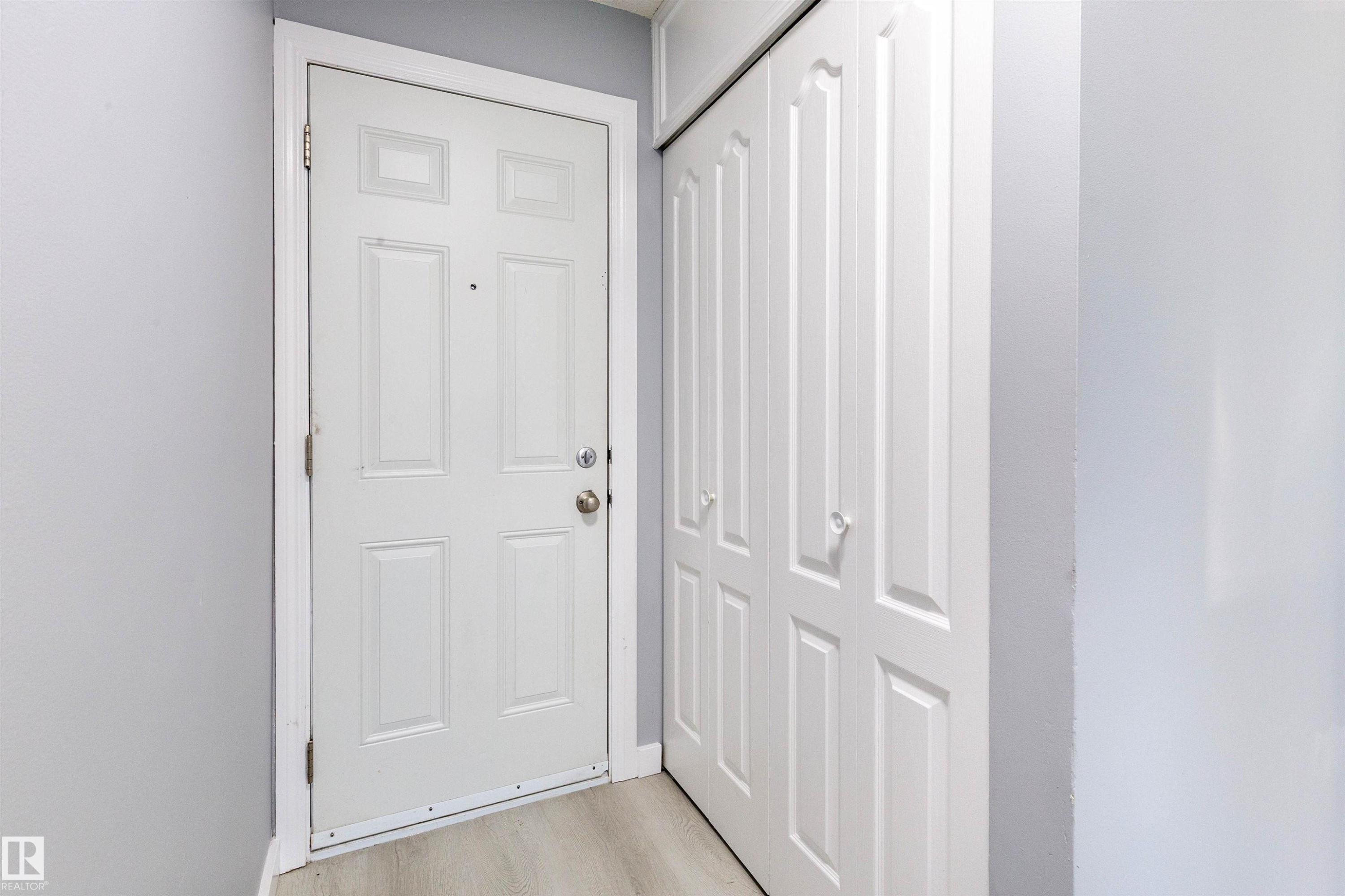 Entryway featuring a paneled door with brushed nickel hardware, light-toned wood-finish flooring, and a multi-panel bifold closet door - 547 Dunluce Road, Edmonton, AB - Indoor Photo Showing Other Room