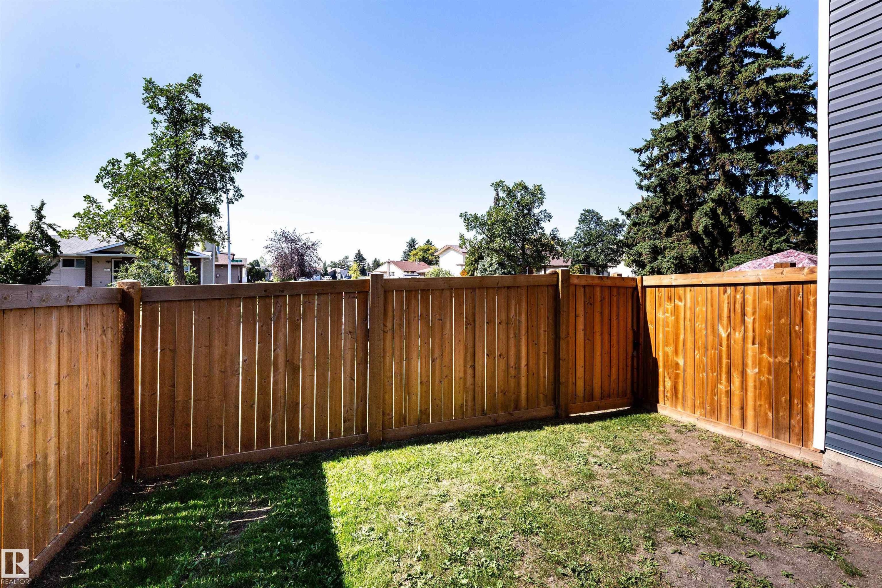 Fenced backyard featuring a wood privacy fence, a wooden gate, and a section of blue horizontal siding - 547 Dunluce Road, Edmonton, AB - Outdoor